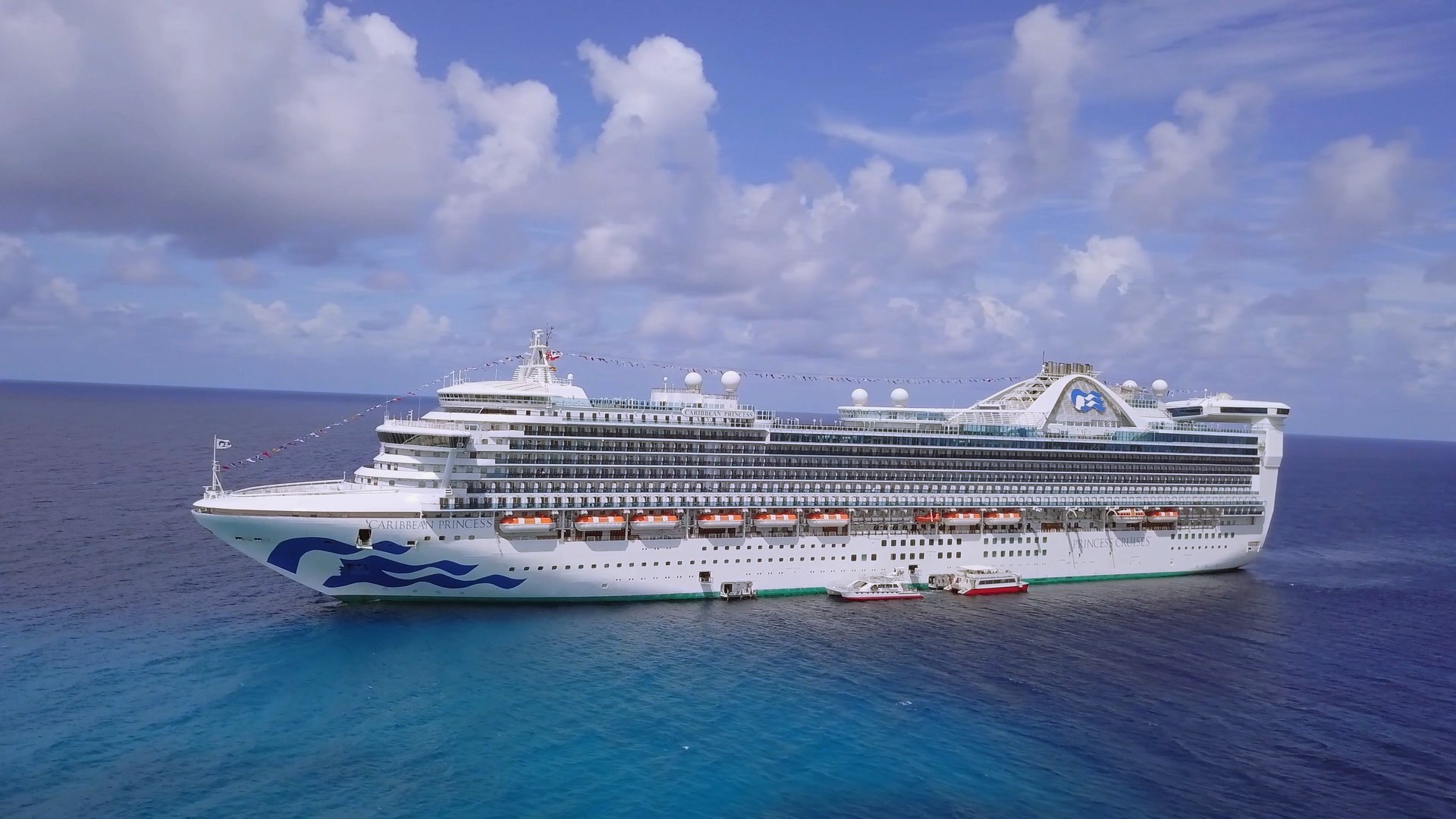 Caribbean Princess at sea from the air with tenders alongside in turquoise water