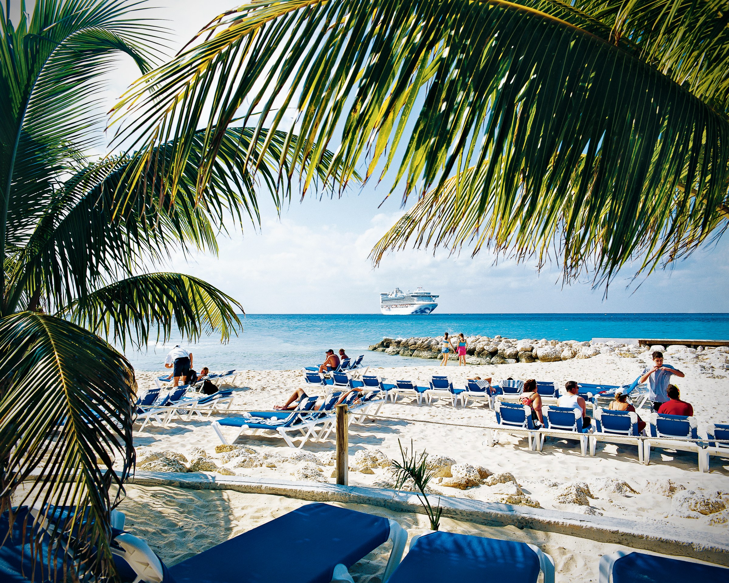 Caribbean Princess at anchor beyond Princess Cays beach with palms and lounge chairs