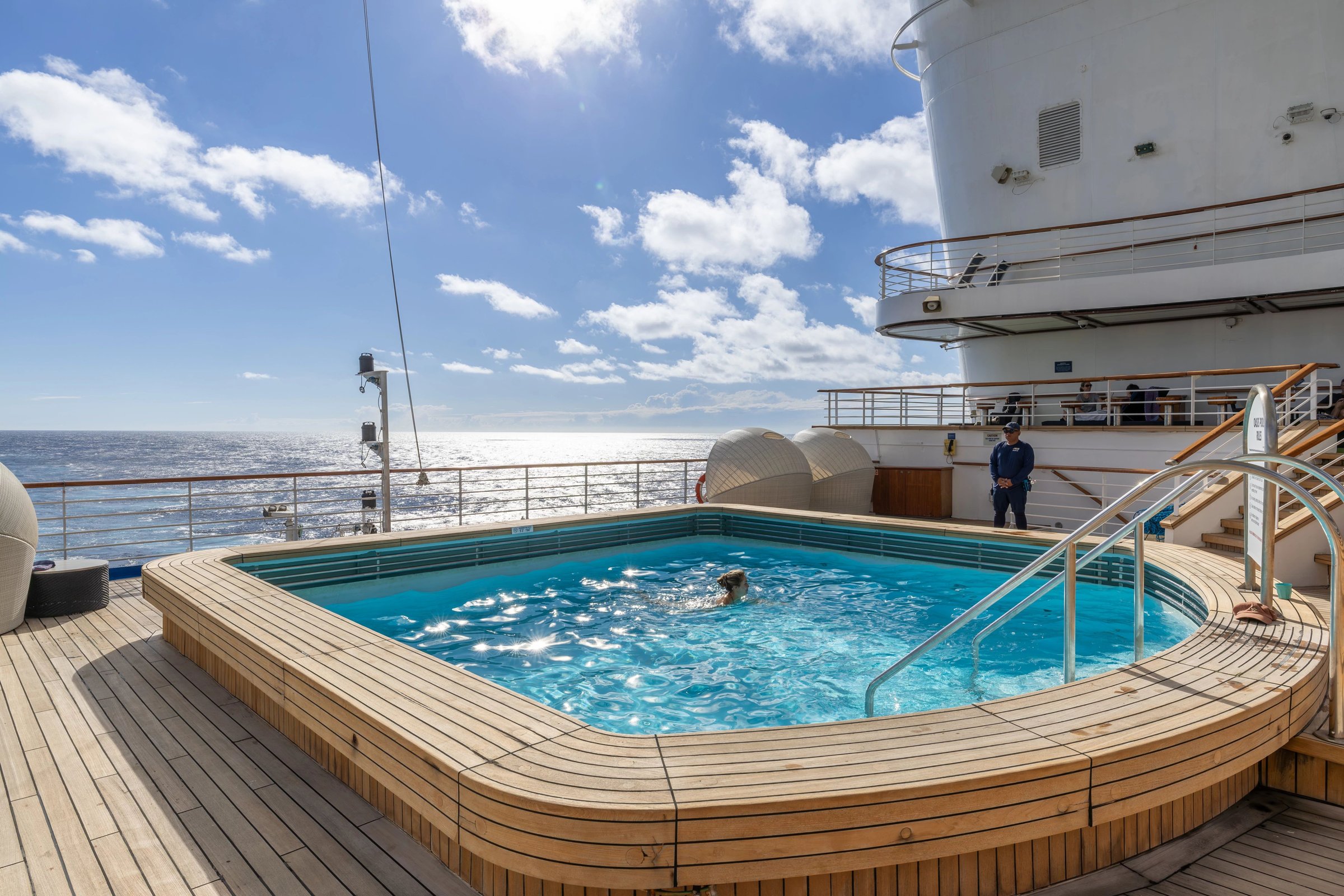 Carnival Adventure Oasis Pool with teak surround on a sunny day with blue sky and clouds