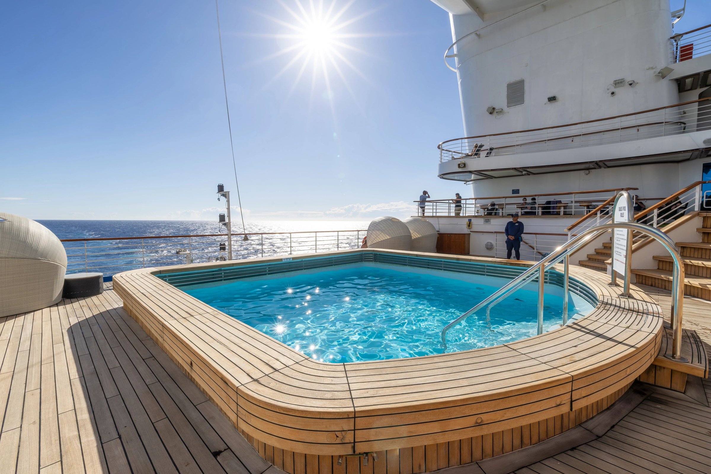 Carnival Adventure Oasis Pool sparkling in bright sun with calm ocean beyond