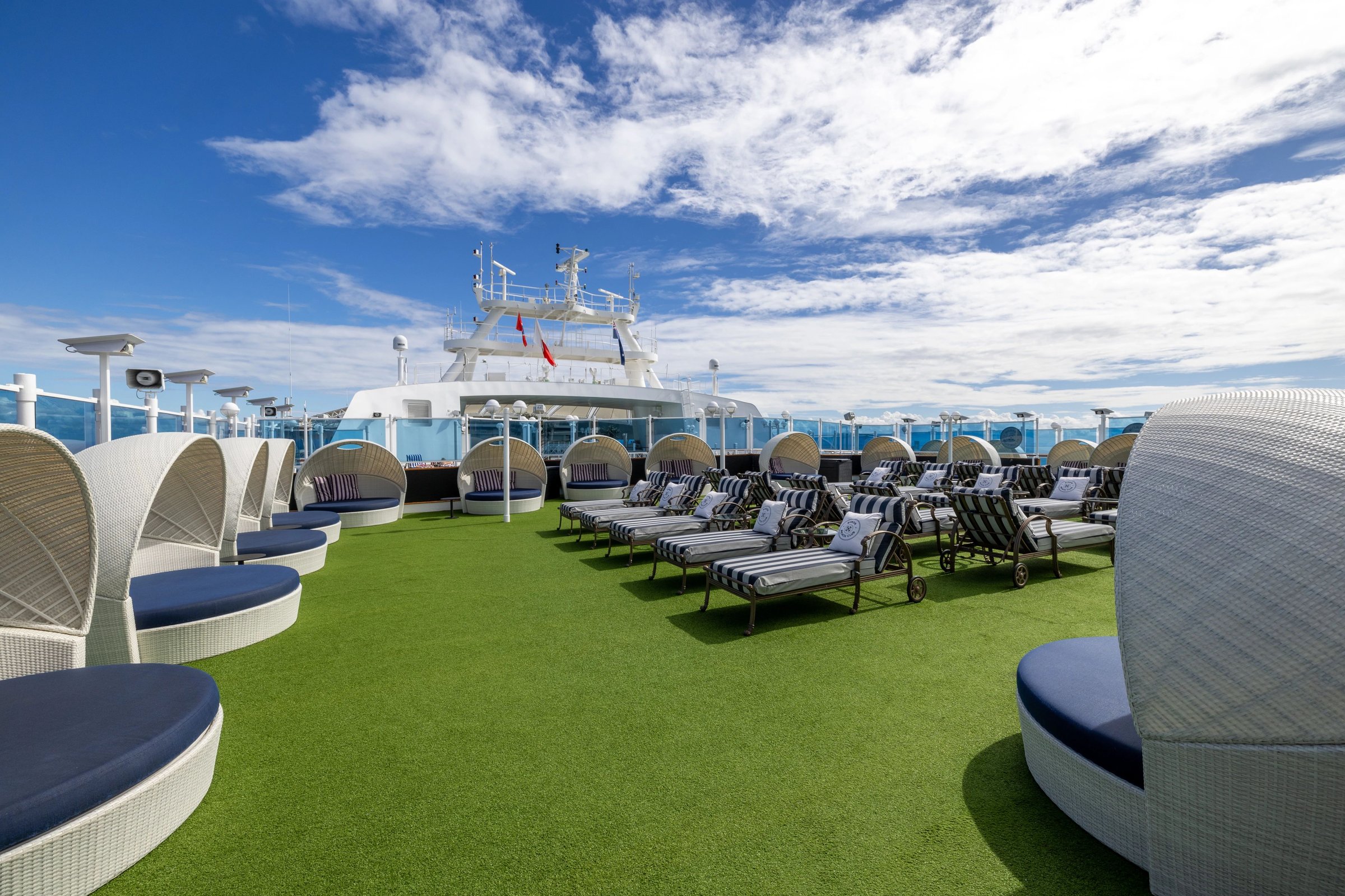 Carnival Adventure Byron Beach Club turf lawn with loungers and cabana daybeds under blue sky