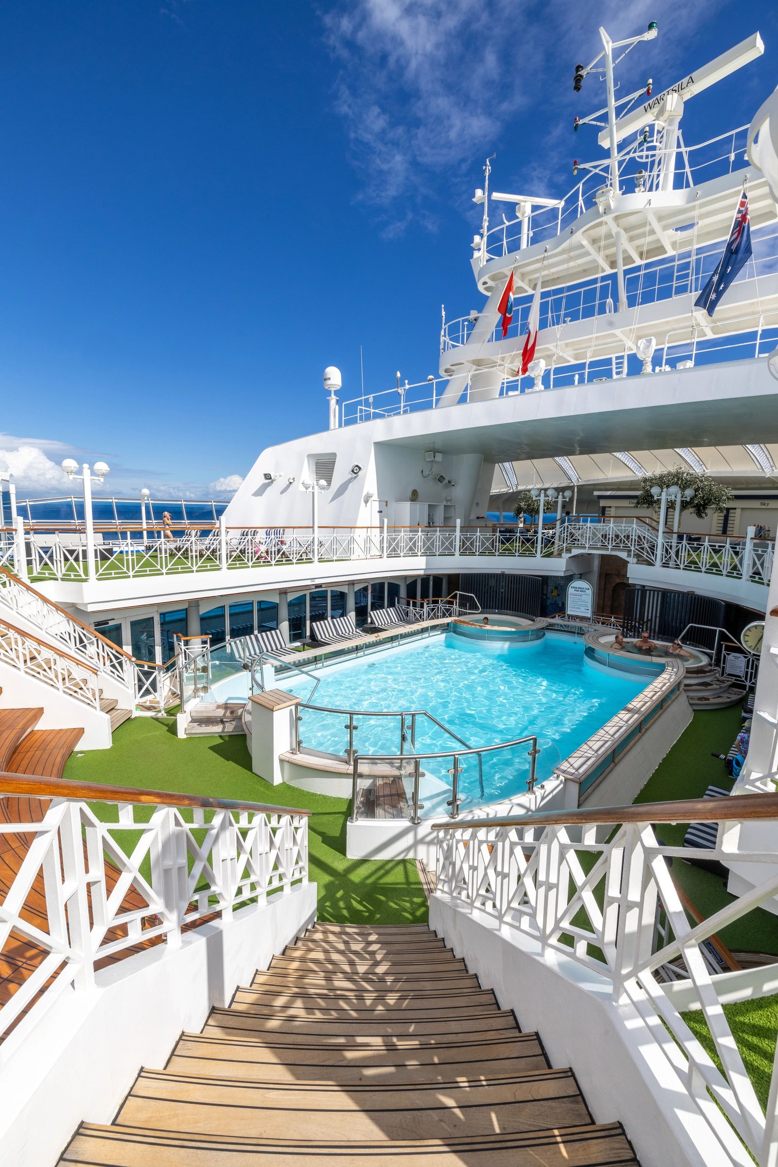 Carnival Adventure aft pool deck and teak stairway seen from above on a sunny day