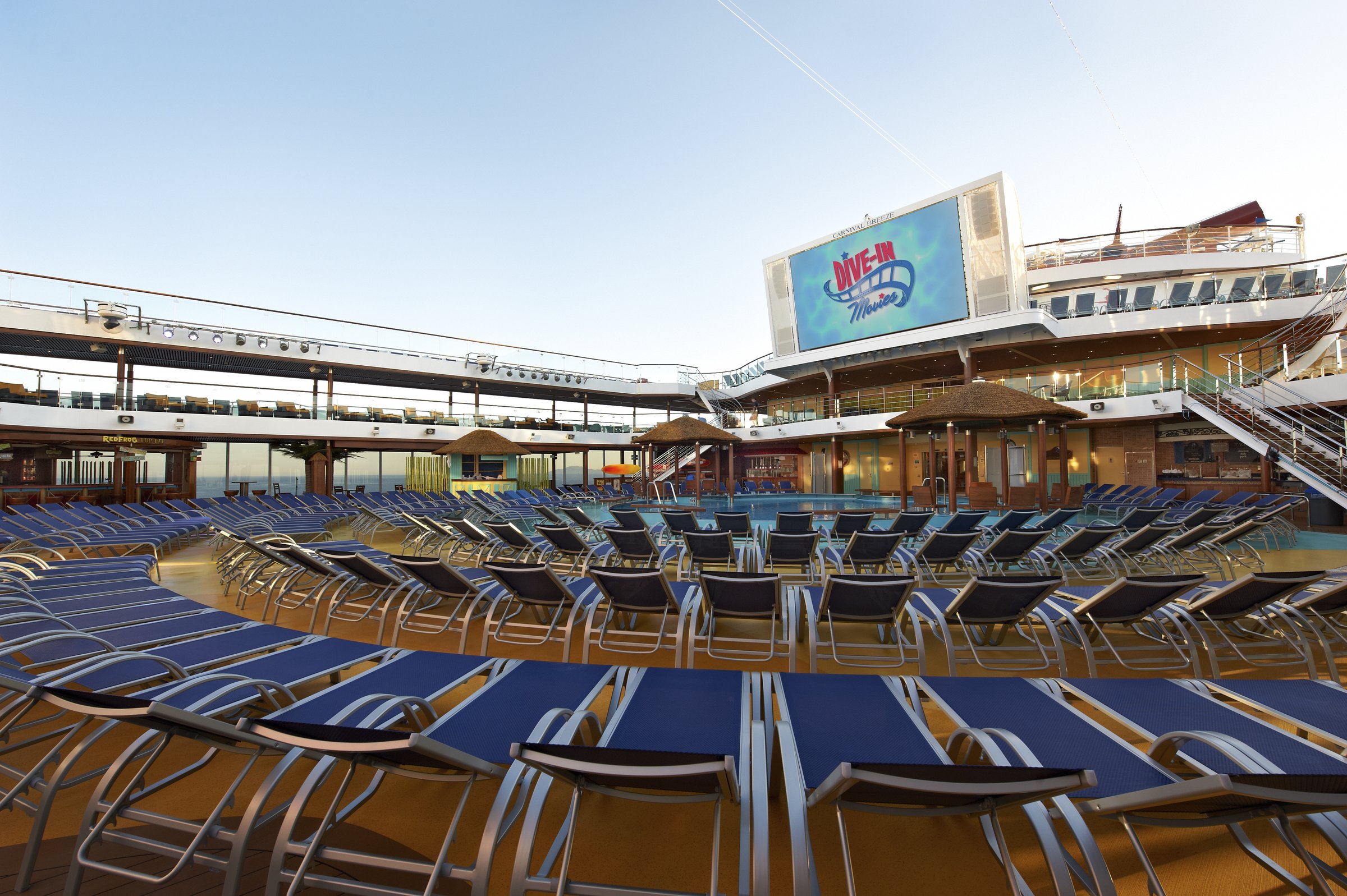 Carnival Breeze main pool deck with rows of blue loungers and the large Dive-In movie screen