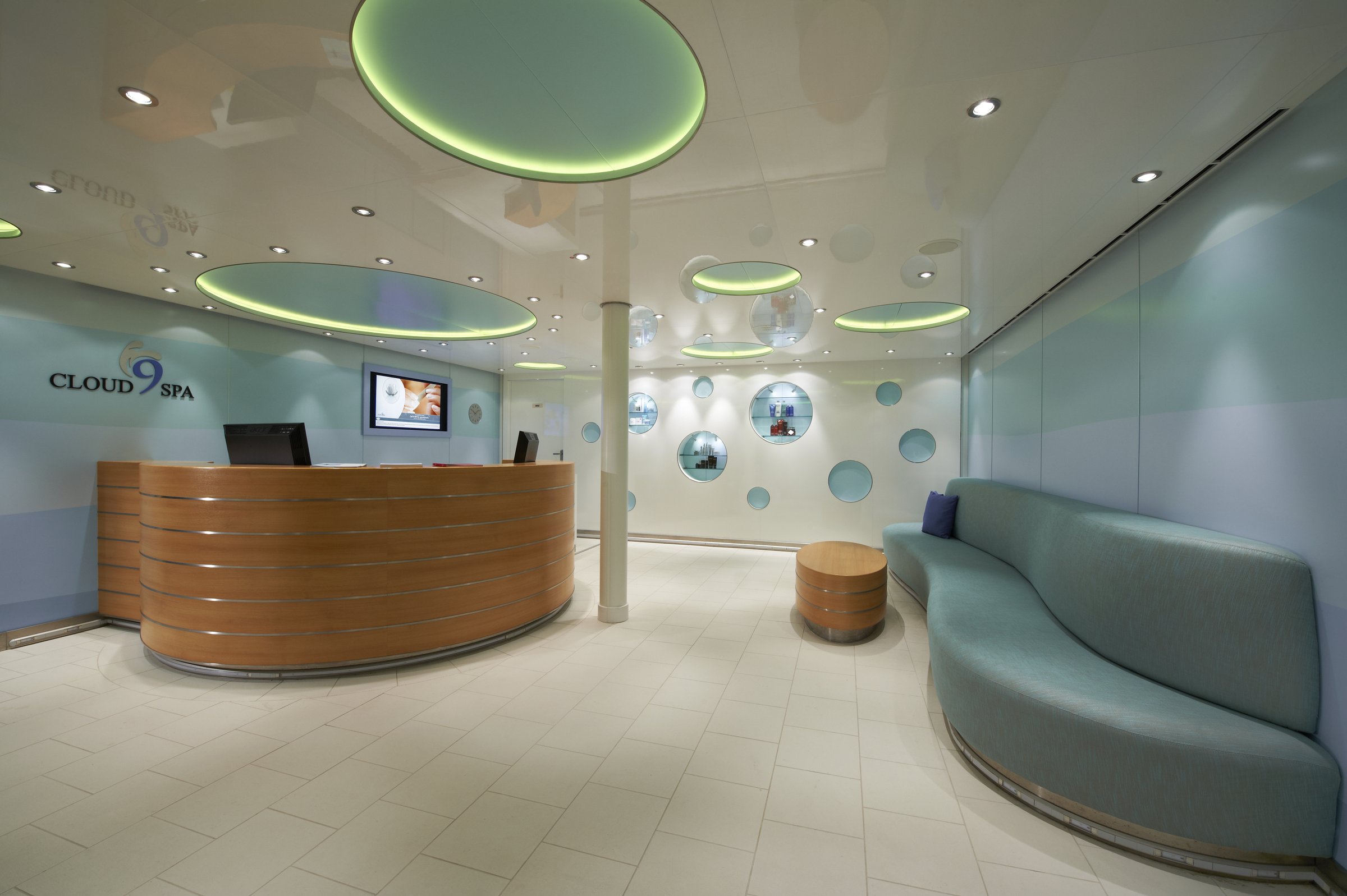 Carnival Breeze Cloud 9 Spa entrance with a curved wooden reception desk and a circular-light ceiling