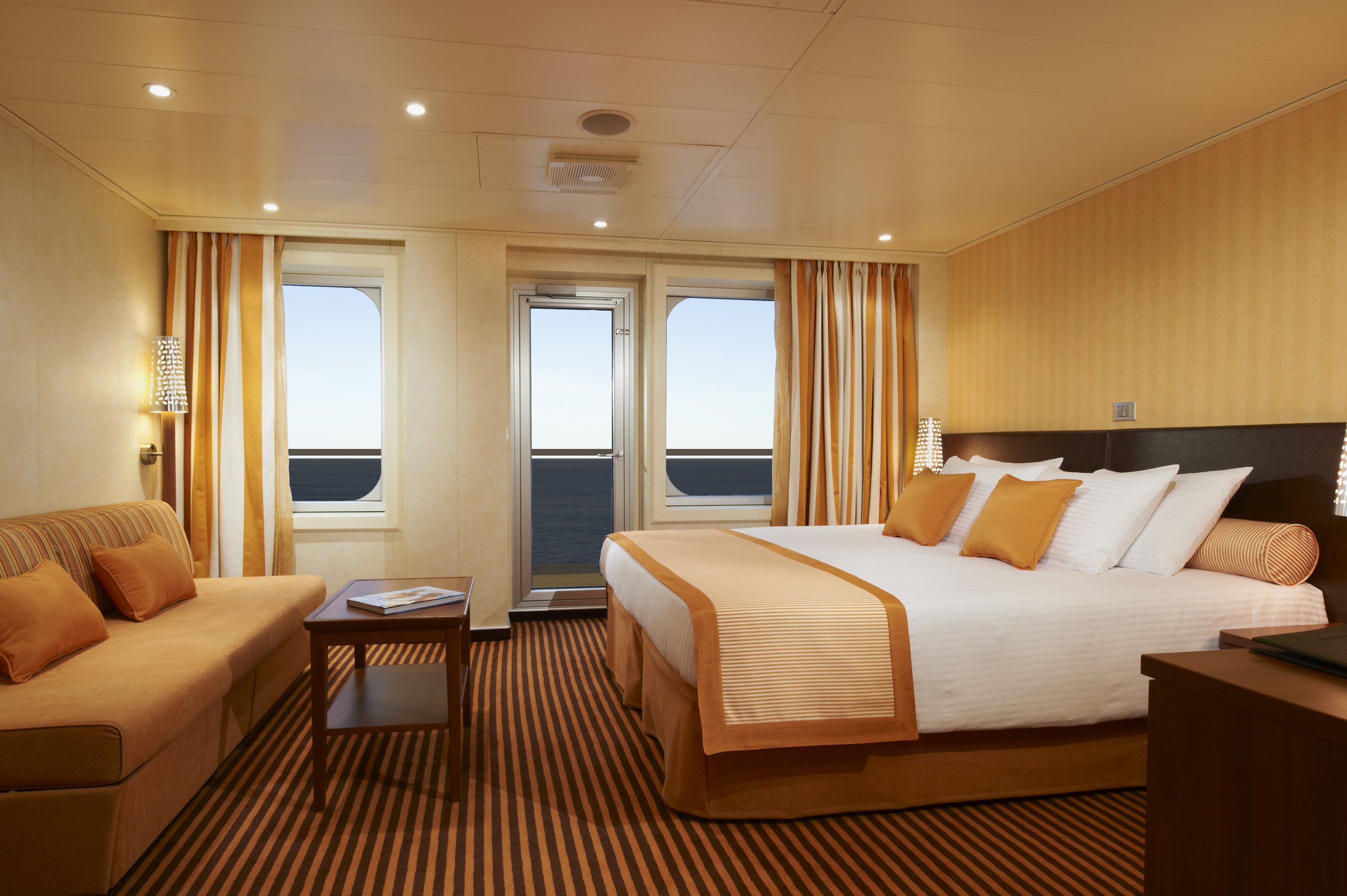 Carnival Breeze Ocean Suite with a king bed, sofa and balcony doors