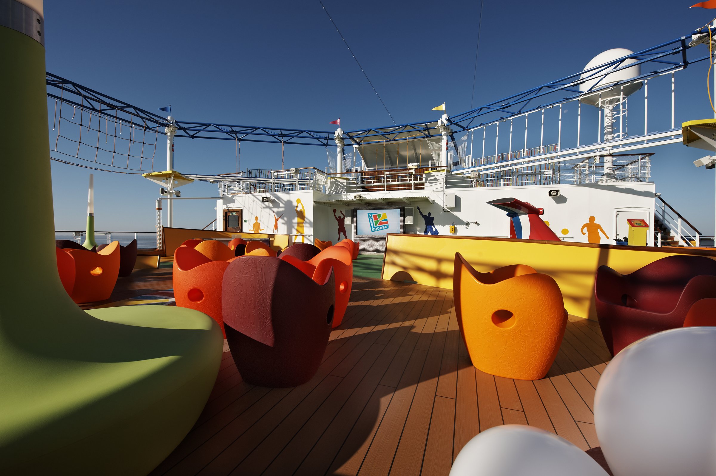 Carnival Breeze sports deck with colourful lounge seats and the ropes course overhead