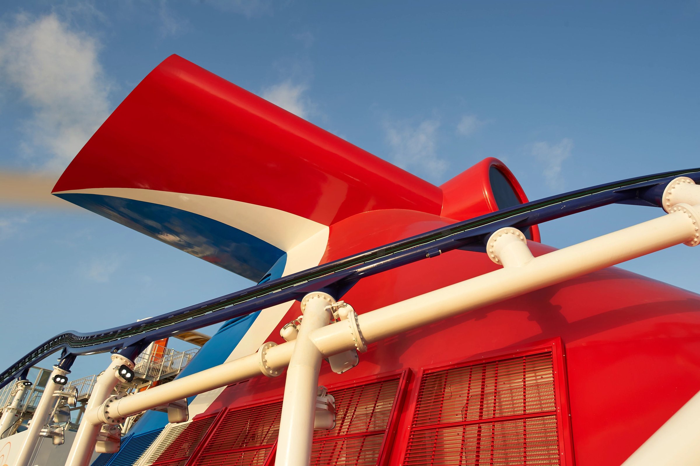 Carnival Celebration red whale-tail funnel with the BOLT roller coaster track against a blue sky