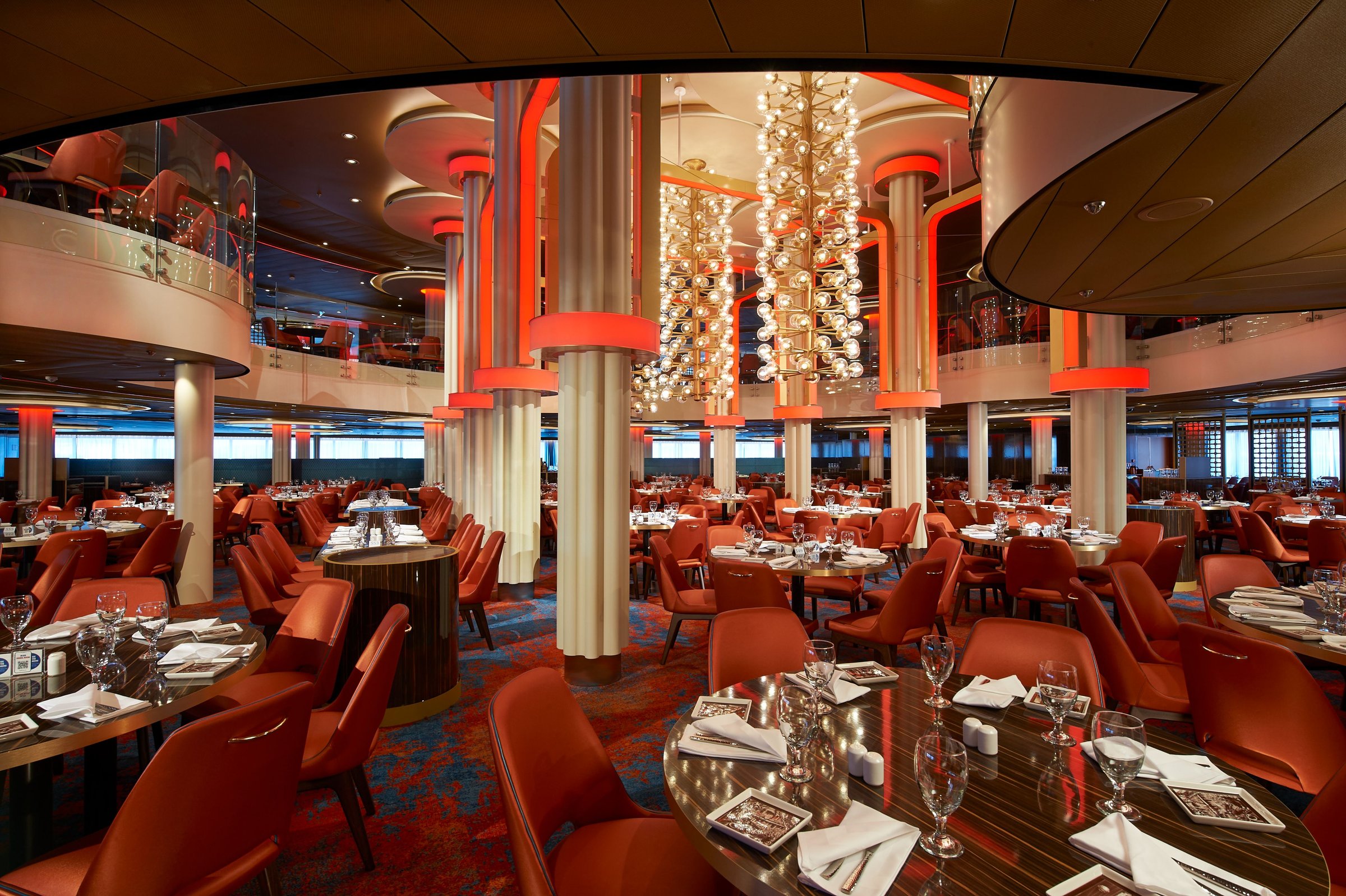 Carnival Celebration Festivale dining room with orange chairs and chandelier columns