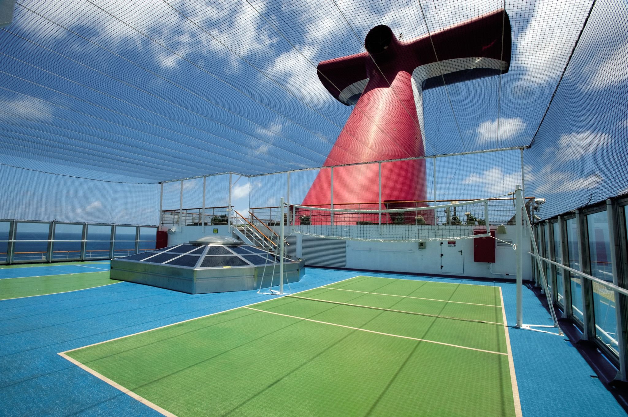 Carnival Conquest sports court under netting with red Whale Tail funnel and blue sky