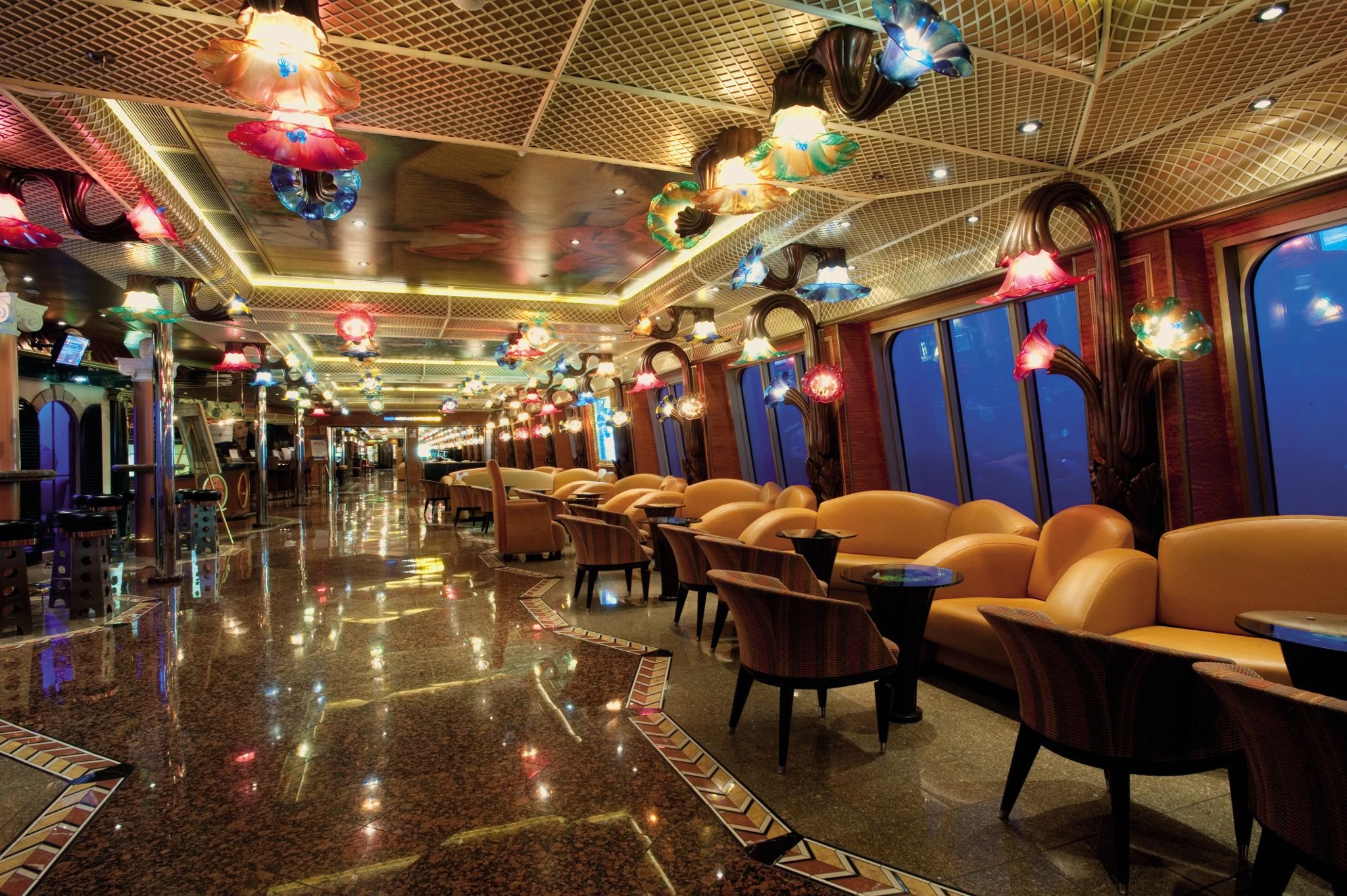 Carnival Conquest Promenade lounge area with orange armchairs and decorative glass lighting