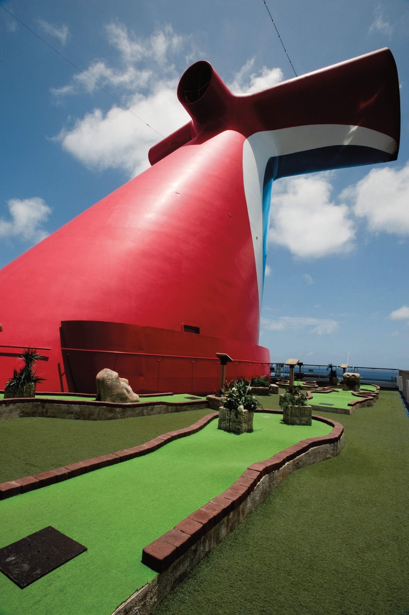 Carnival Conquest mini golf course beneath the red funnel on a bright sunny day