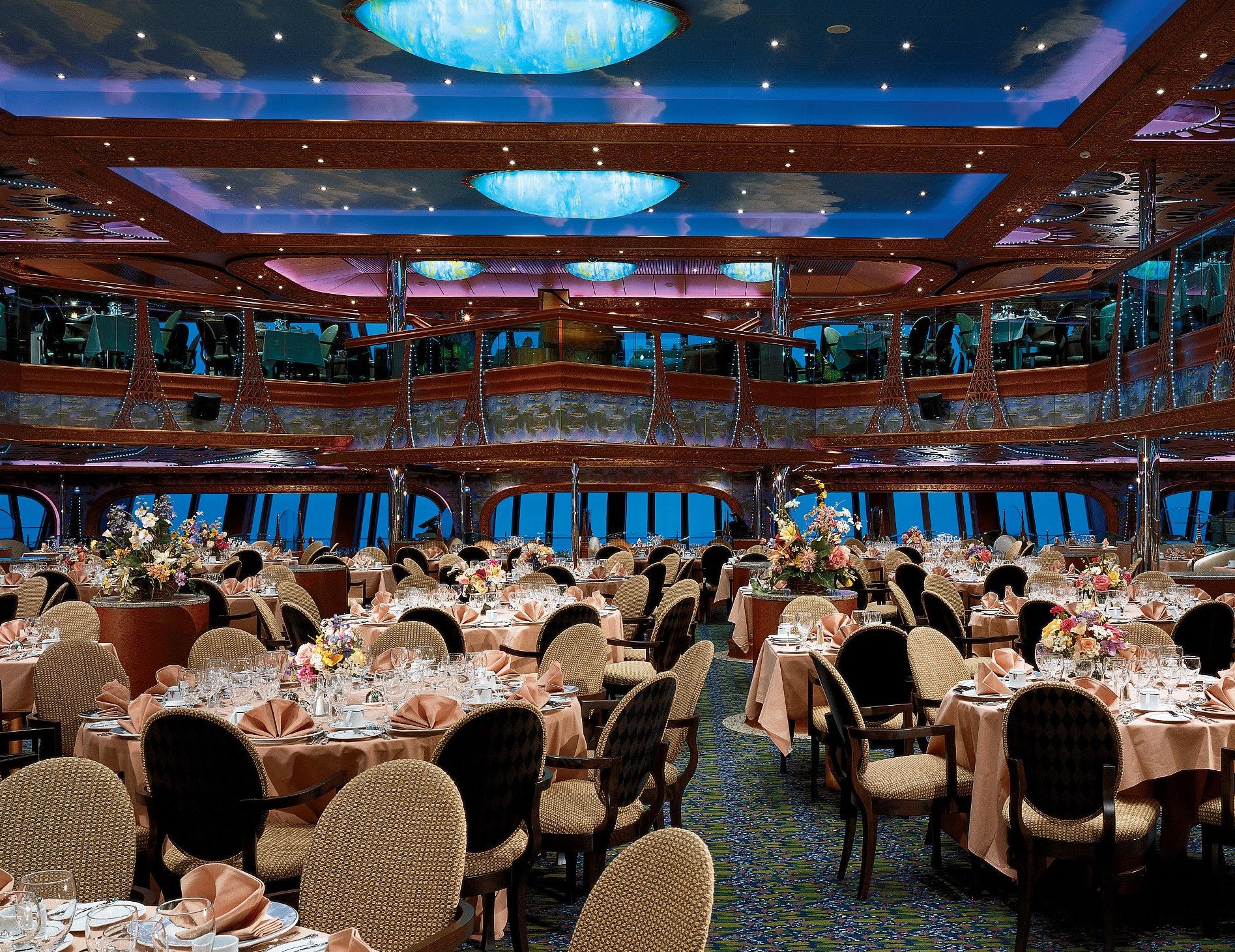 Carnival Conquest aft dining room set for dinner beneath illuminated ceiling