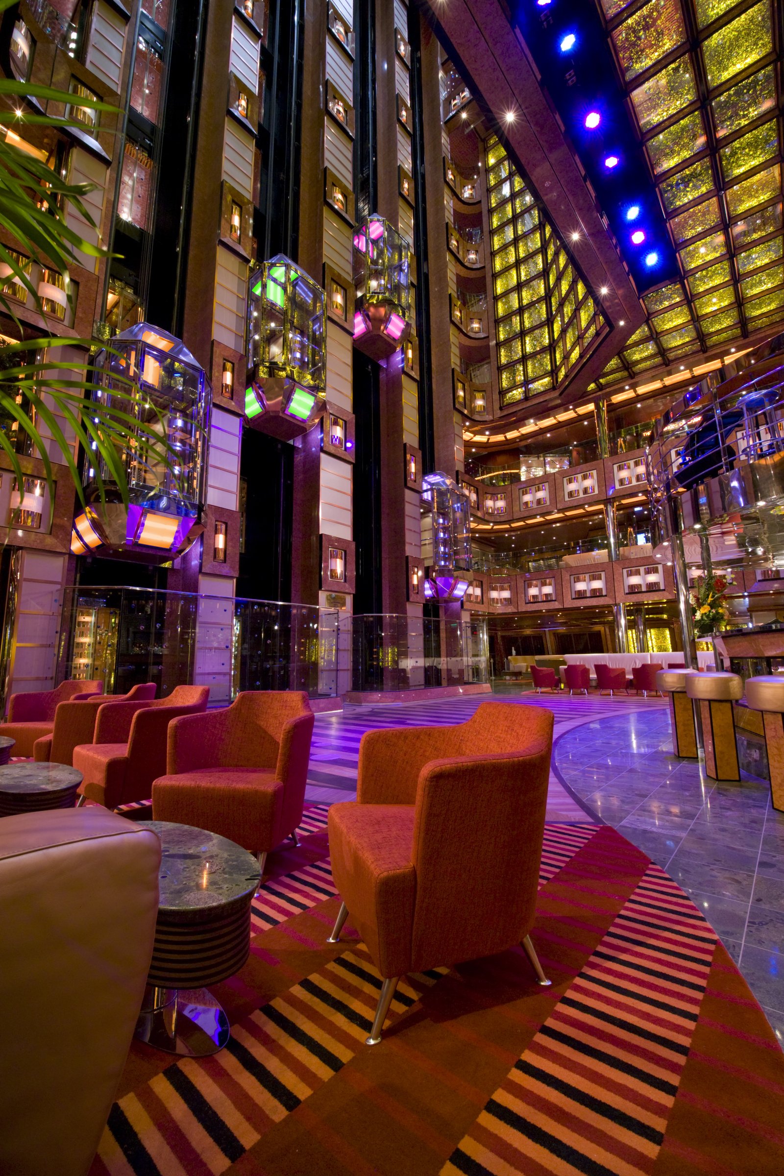 Carnival Dream multi-deck atrium with glass elevators, orange armchairs and a striped carpet