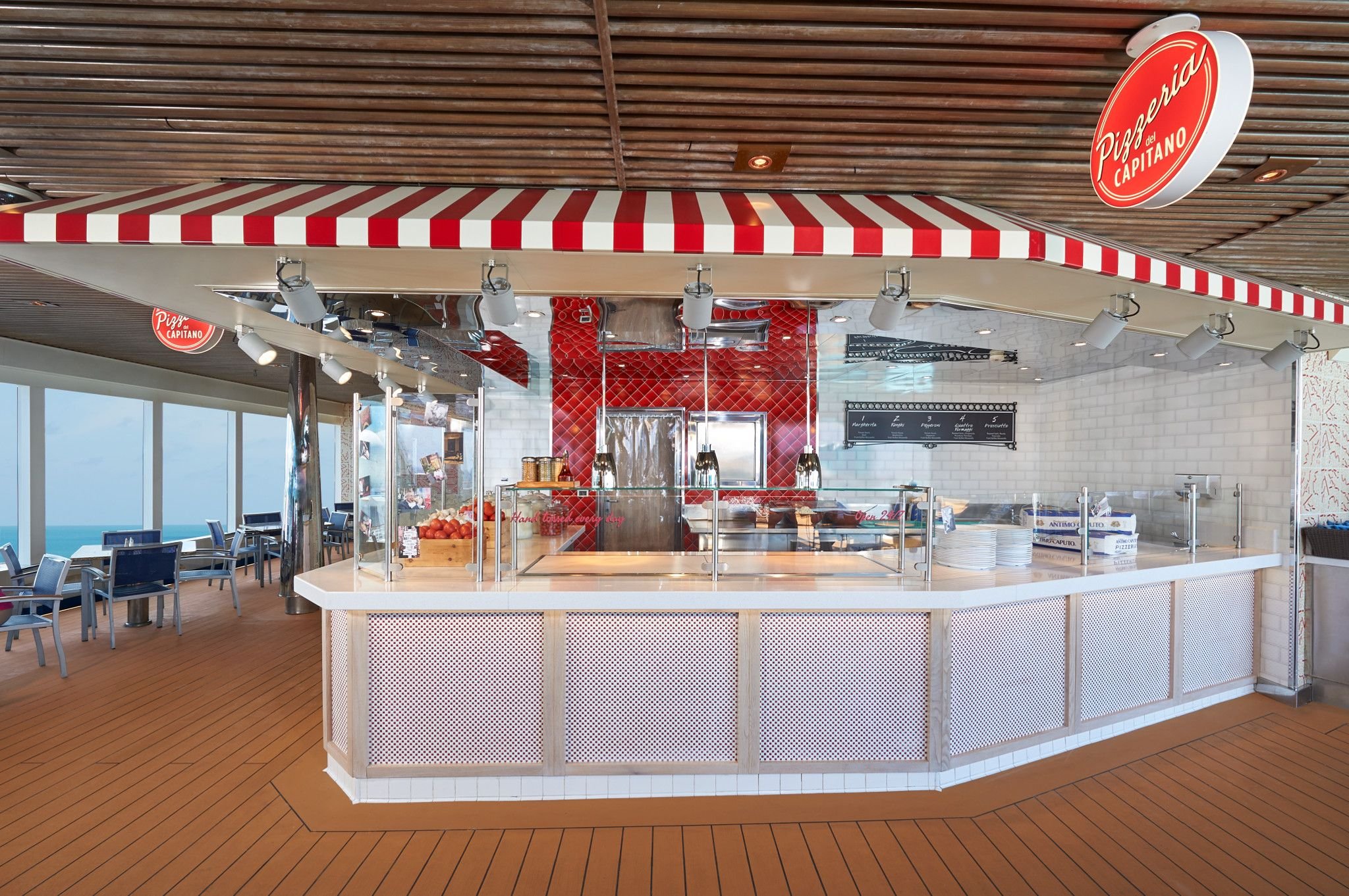 Carnival Dream Pizzeria counter with a red and white striped awning and ocean-view seating