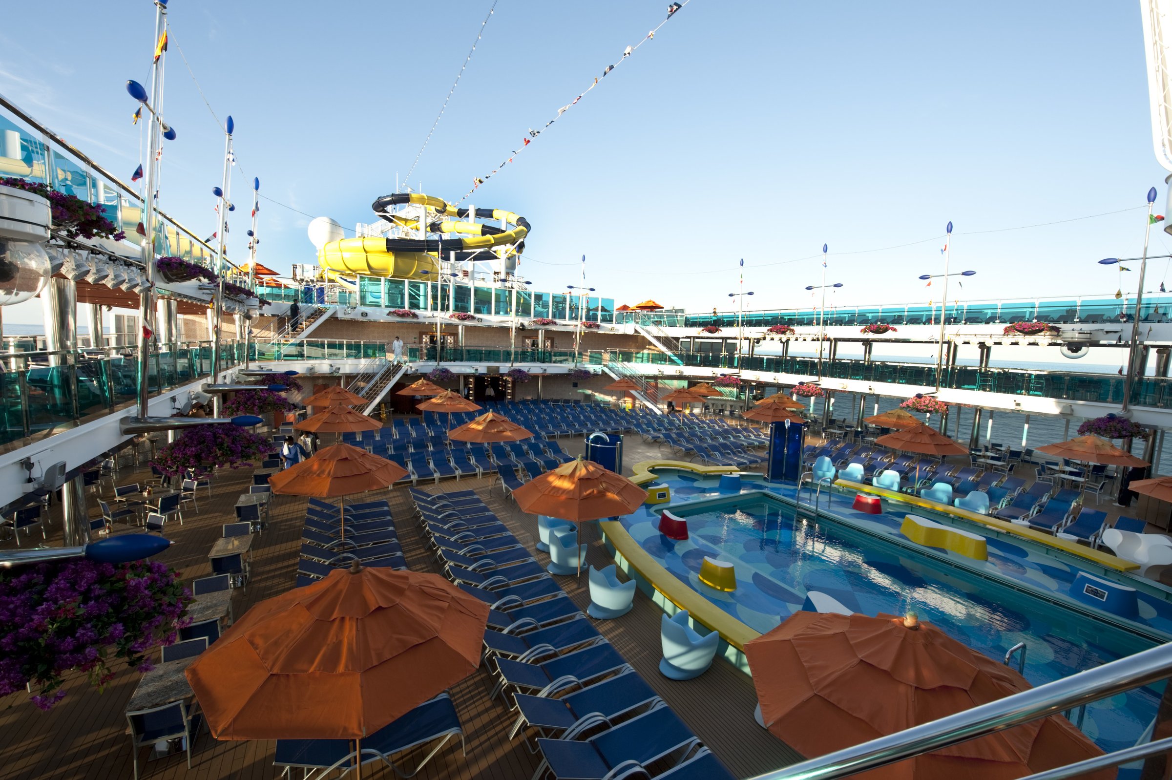 Carnival Dream Waves midship pool deck with orange umbrellas, loungers and the WaterWorks slides beyond