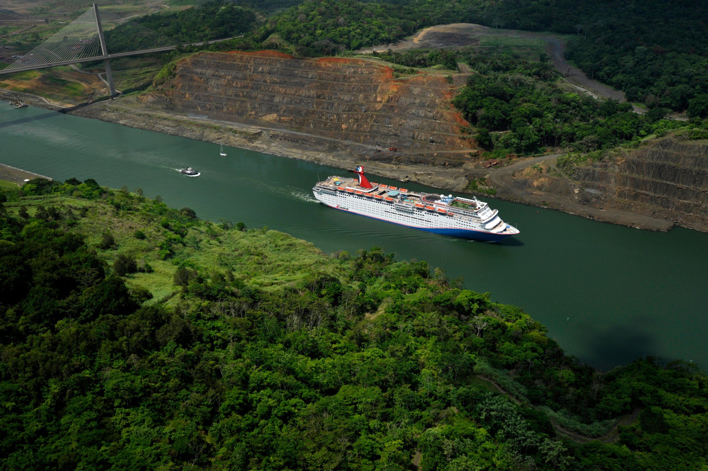 Carnival Elation aerial transiting the Panama Canal past green hills, bright daylight