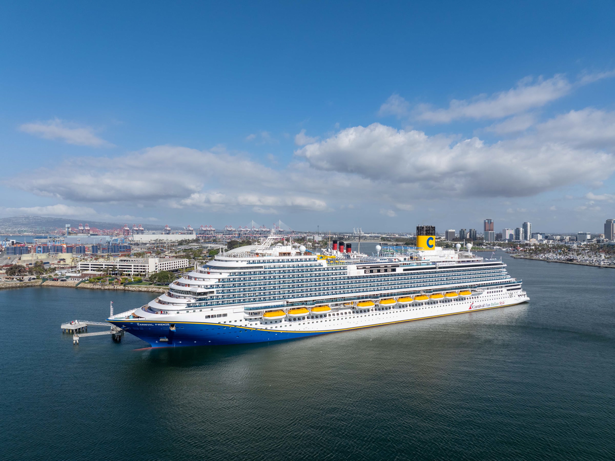 Carnival Firenze aerial at Long Beach harbor under sunny sky with port skyline