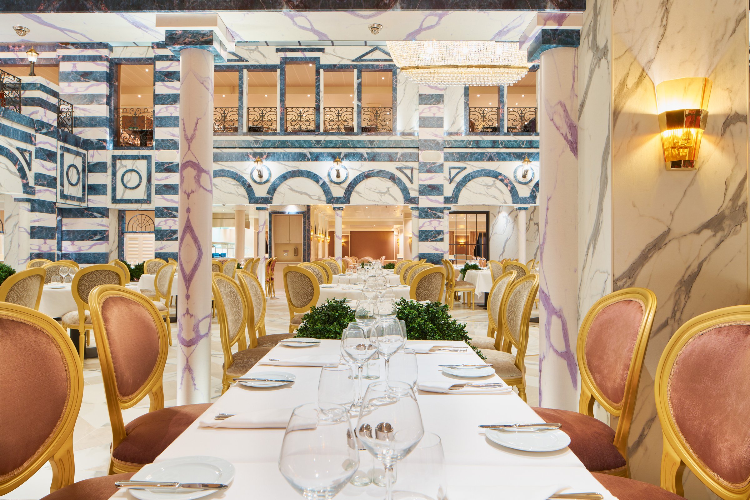 Carnival Firenze Ristorante dei Medici with white-clothed tables, gold chairs and blue-and-white marble columns