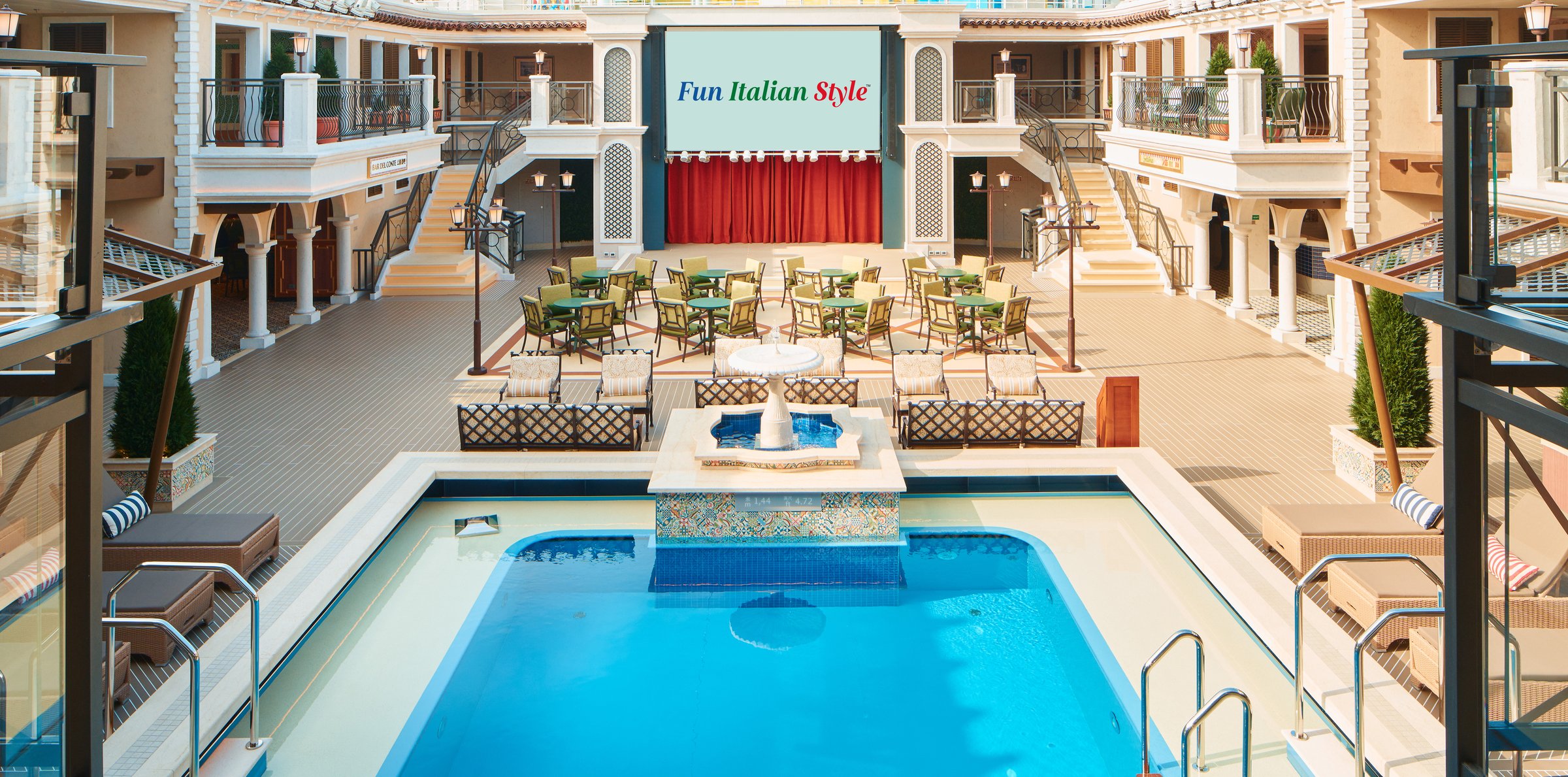 Carnival Firenze Versilia pool deck with a sparkling blue pool, loungers and a stage screen in a Venetian-style piazza
