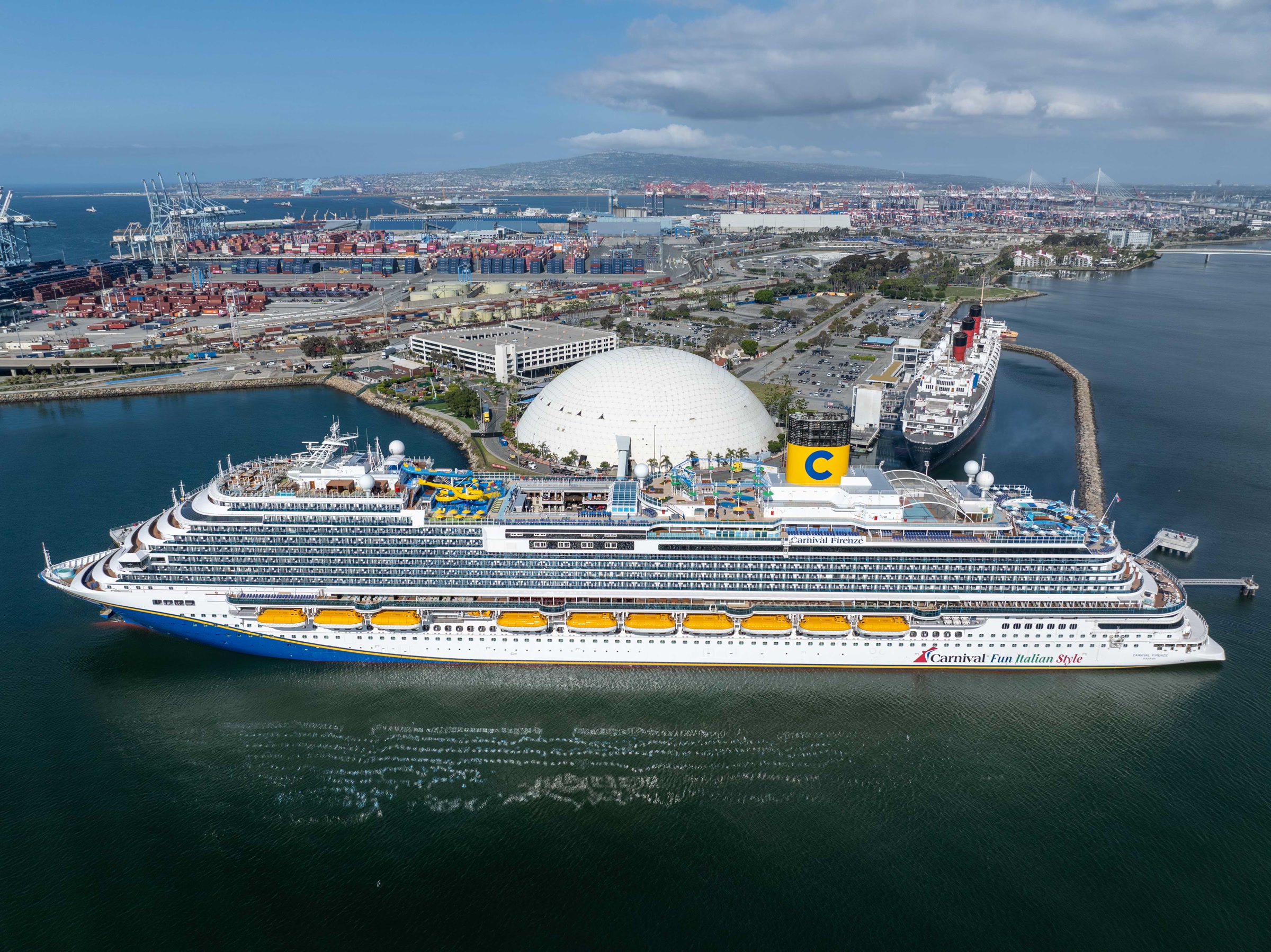Carnival Firenze docked at Long Beach Cruise Terminal aerial with Queen Mary and dome, sunny daylight