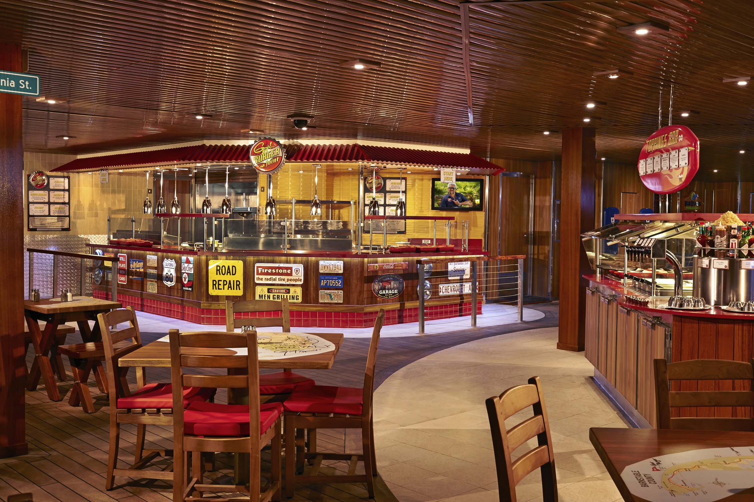 Carnival Freedom Guy's Burger Joint counter with red-cushioned wooden tables and chairs