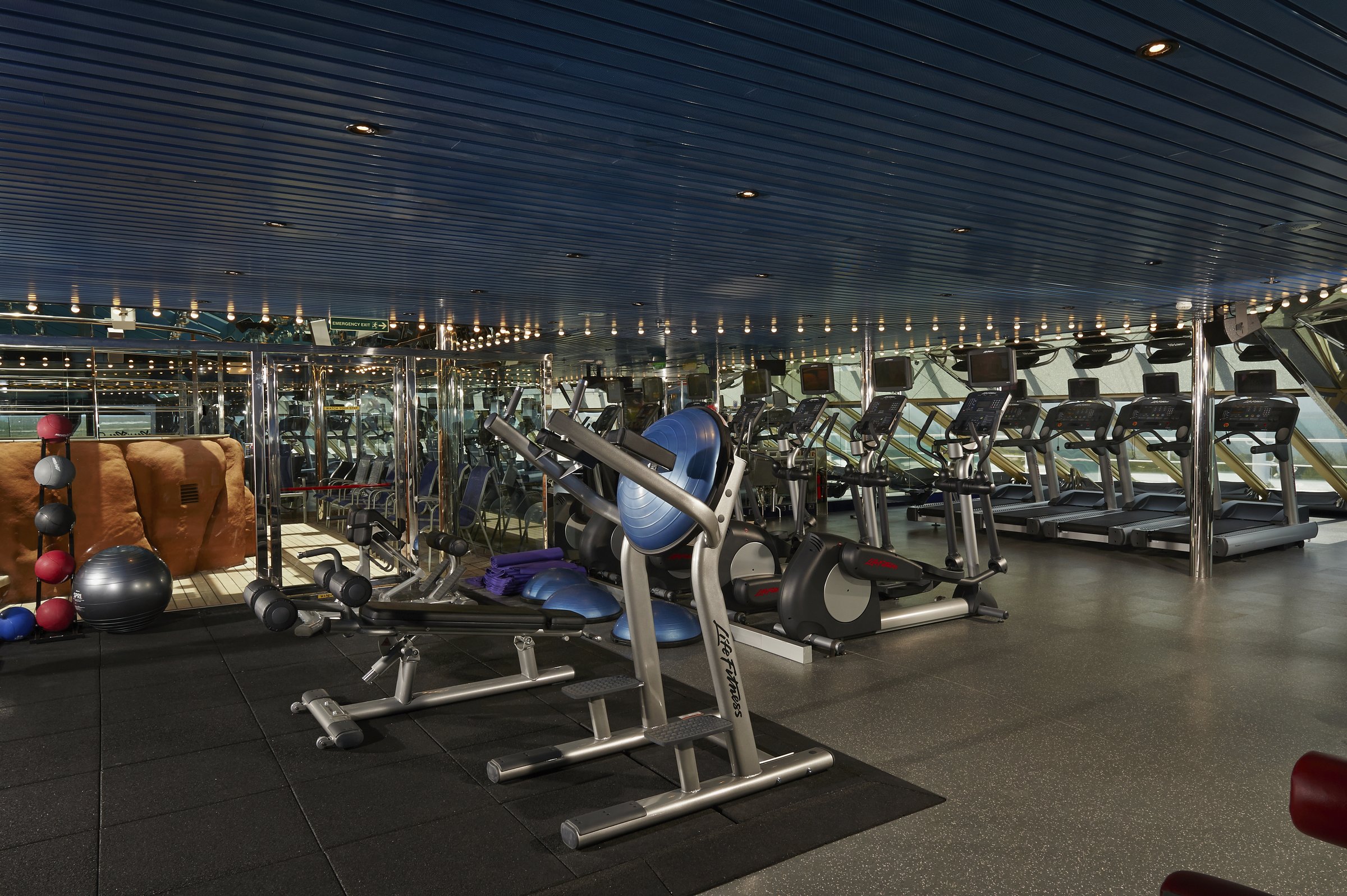 Carnival Freedom fitness center with rows of treadmills, cardio machines and weight benches