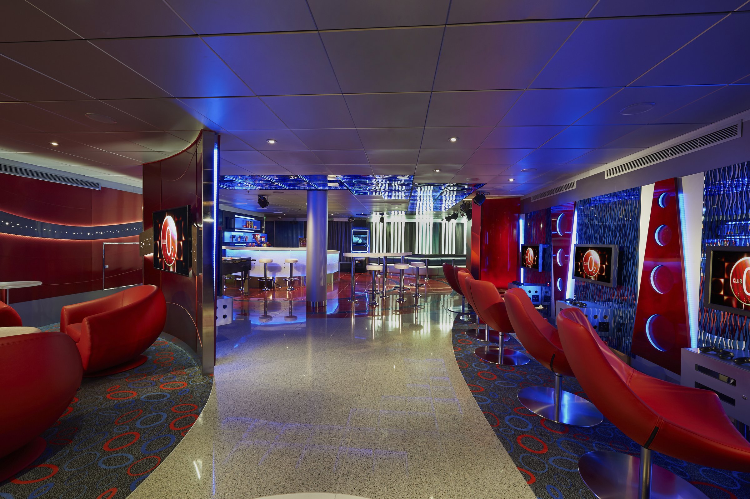 Carnival Freedom Club O2 teen lounge with red swivel seats, booths and a bar counter