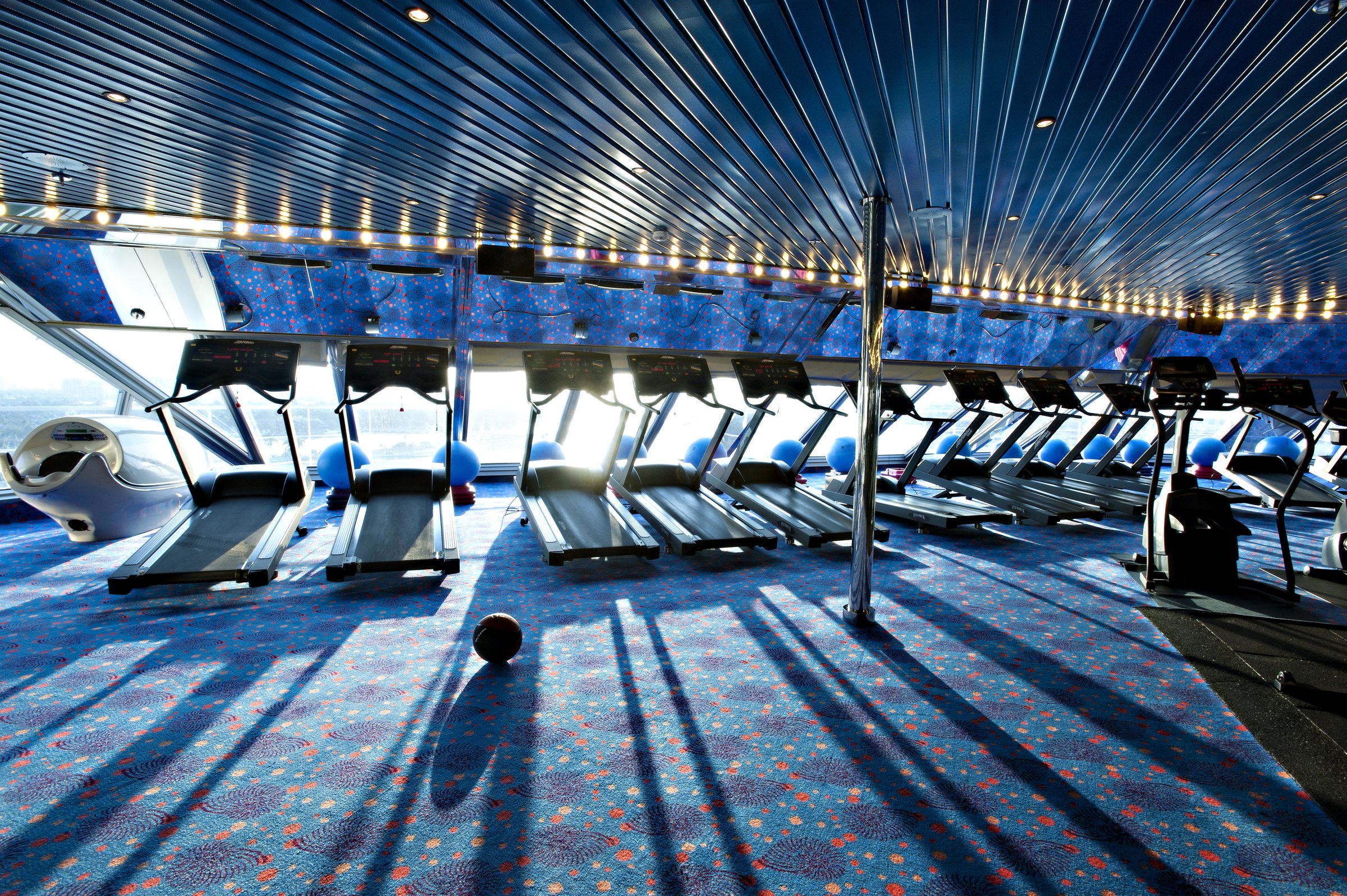 Carnival Glory fitness center with rows of treadmills facing the windows