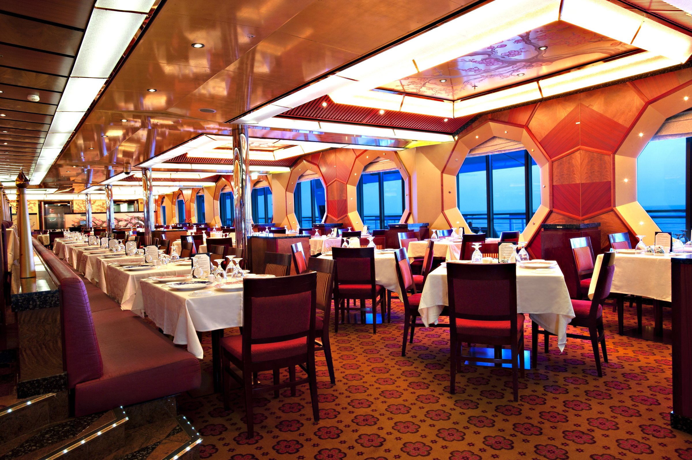 Carnival Glory Golden dining room with white tablecloths and red chairs by the windows