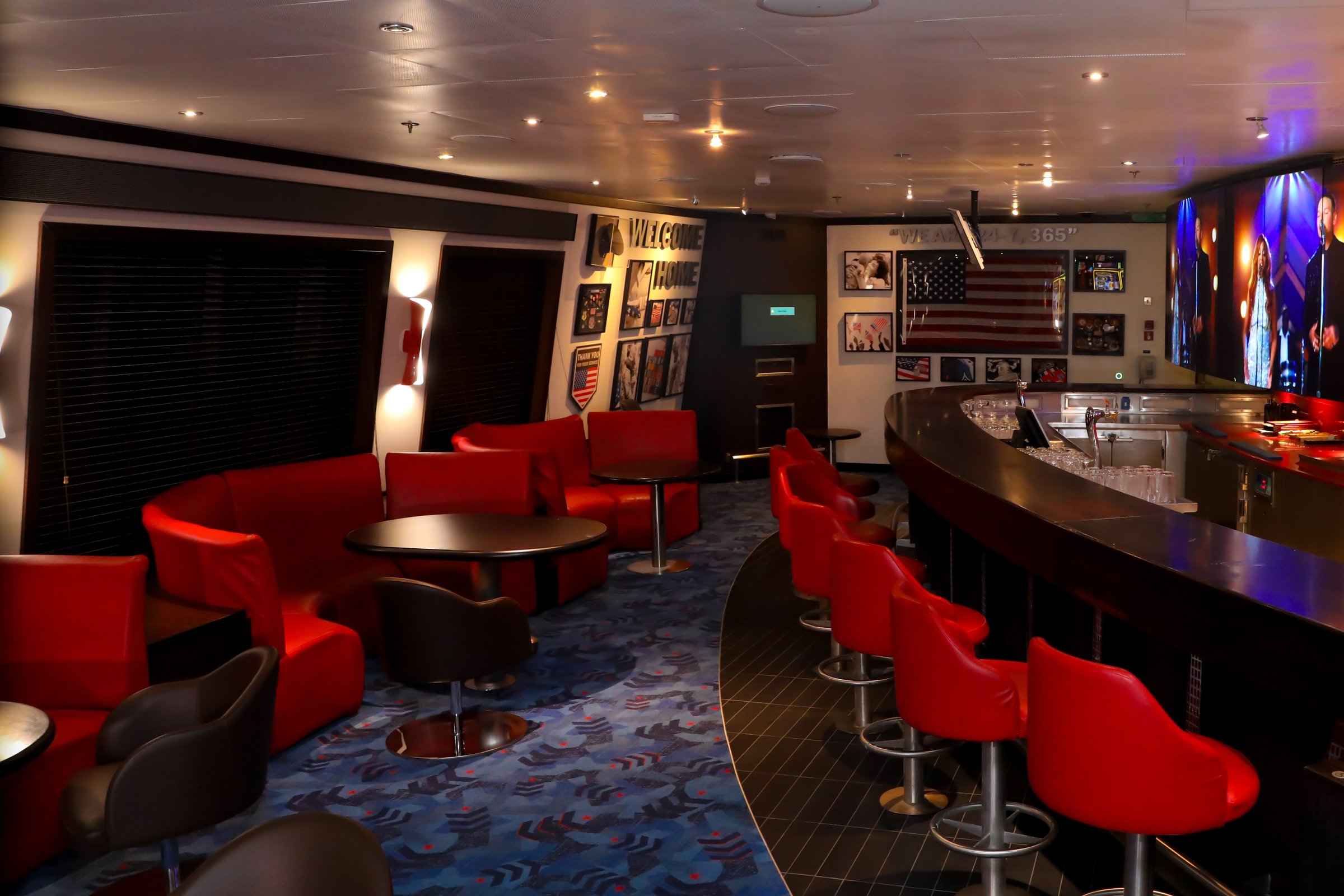 Carnival Glory Heroes Tribute Bar with red lounge seating and a curved bar
