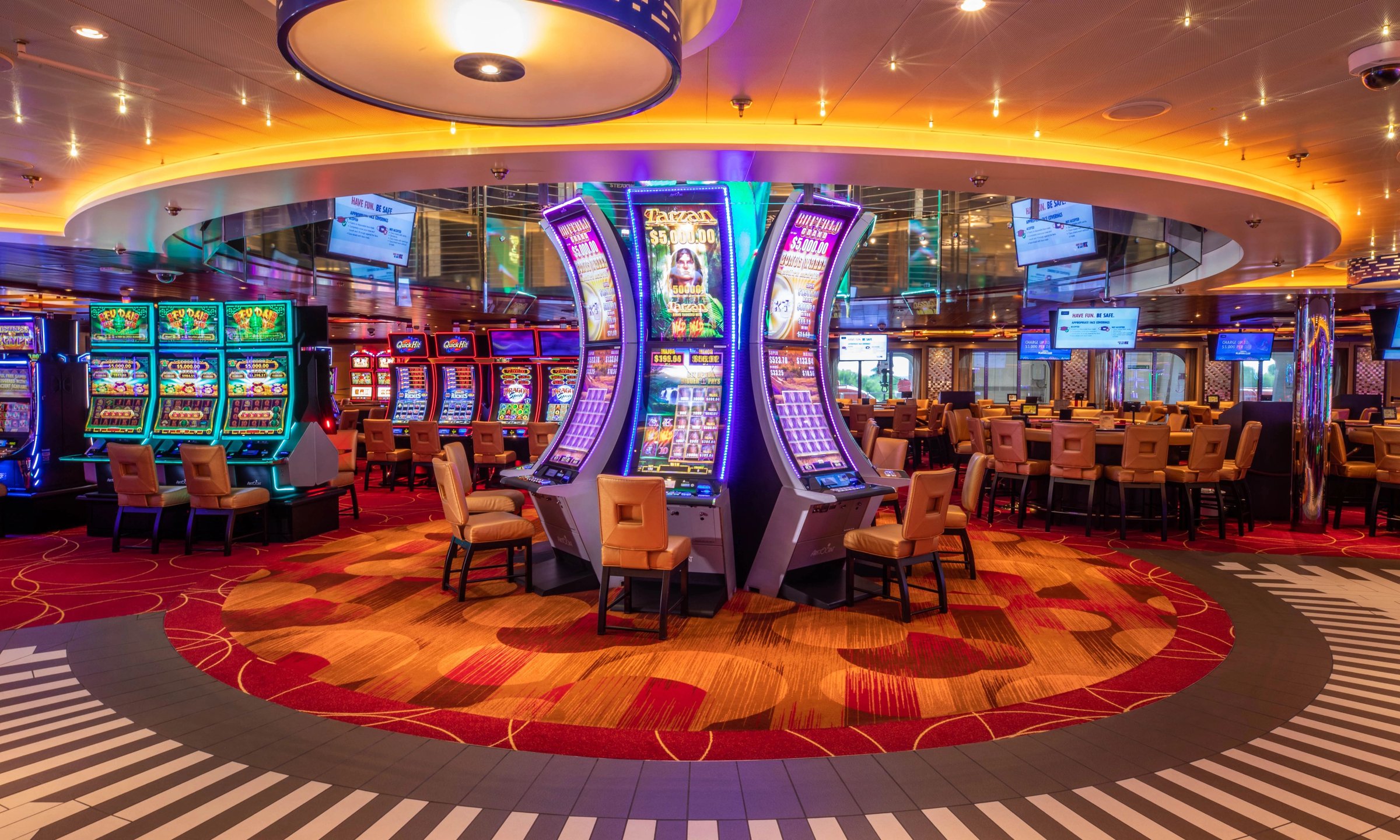 Carnival Horizon casino with slot machines and gaming tables under a lit circular ceiling
