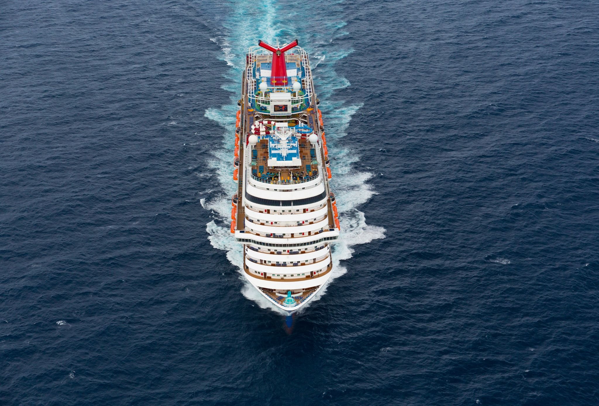 Overhead aerial of Carnival Horizon sailing across deep blue water, trailing a long white wake