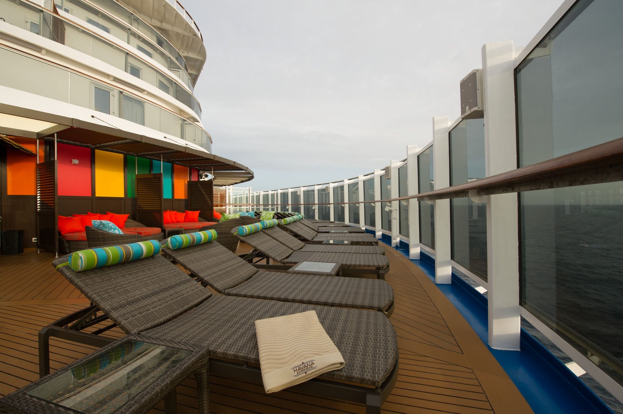 Carnival Horizon Havana deck cabana loungers with striped bolsters along the glass sea railing