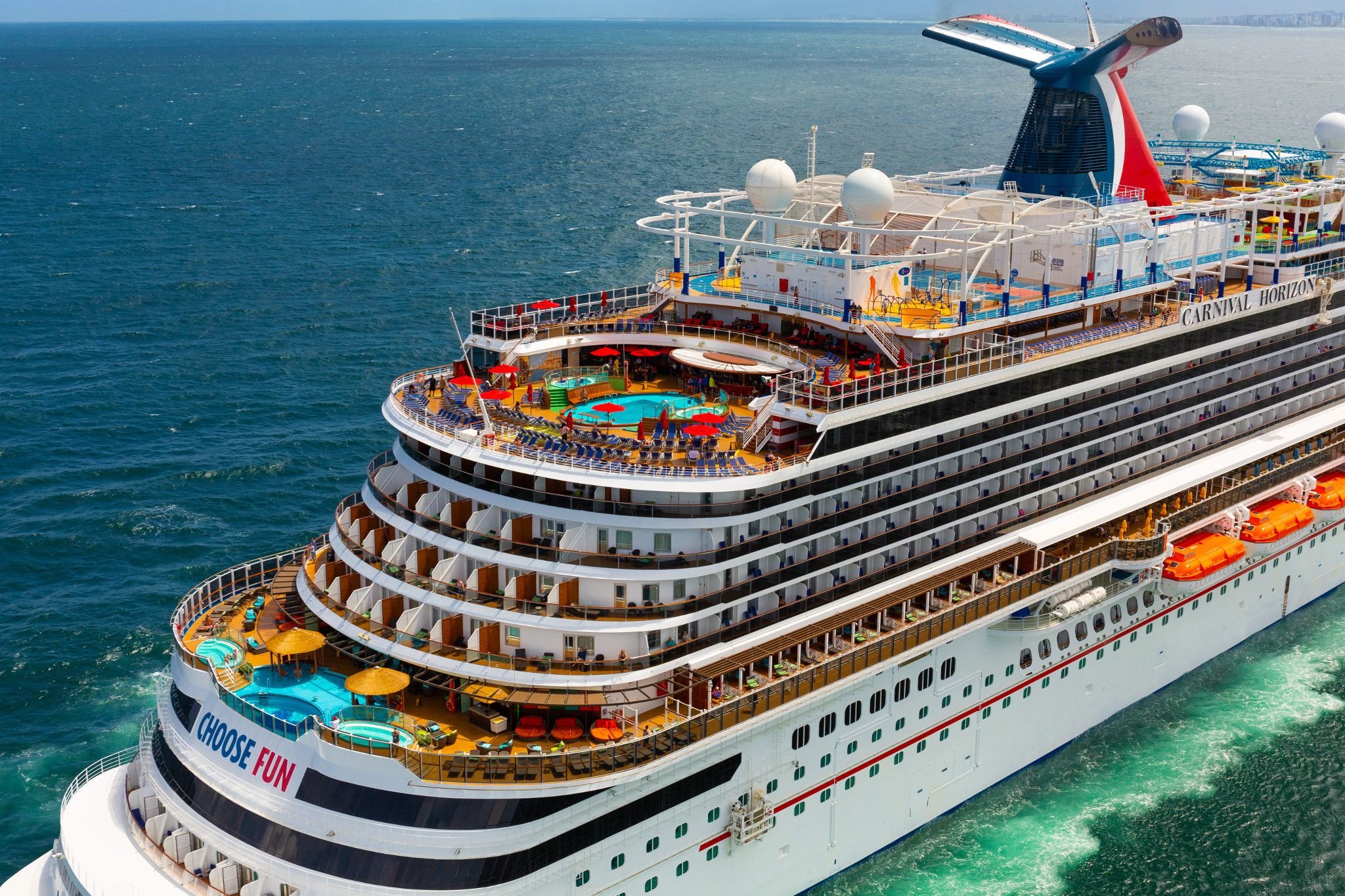 Aerial of Carnival Horizon from the bow quarter, showing the Choose Fun hull lettering and tiered forward decks