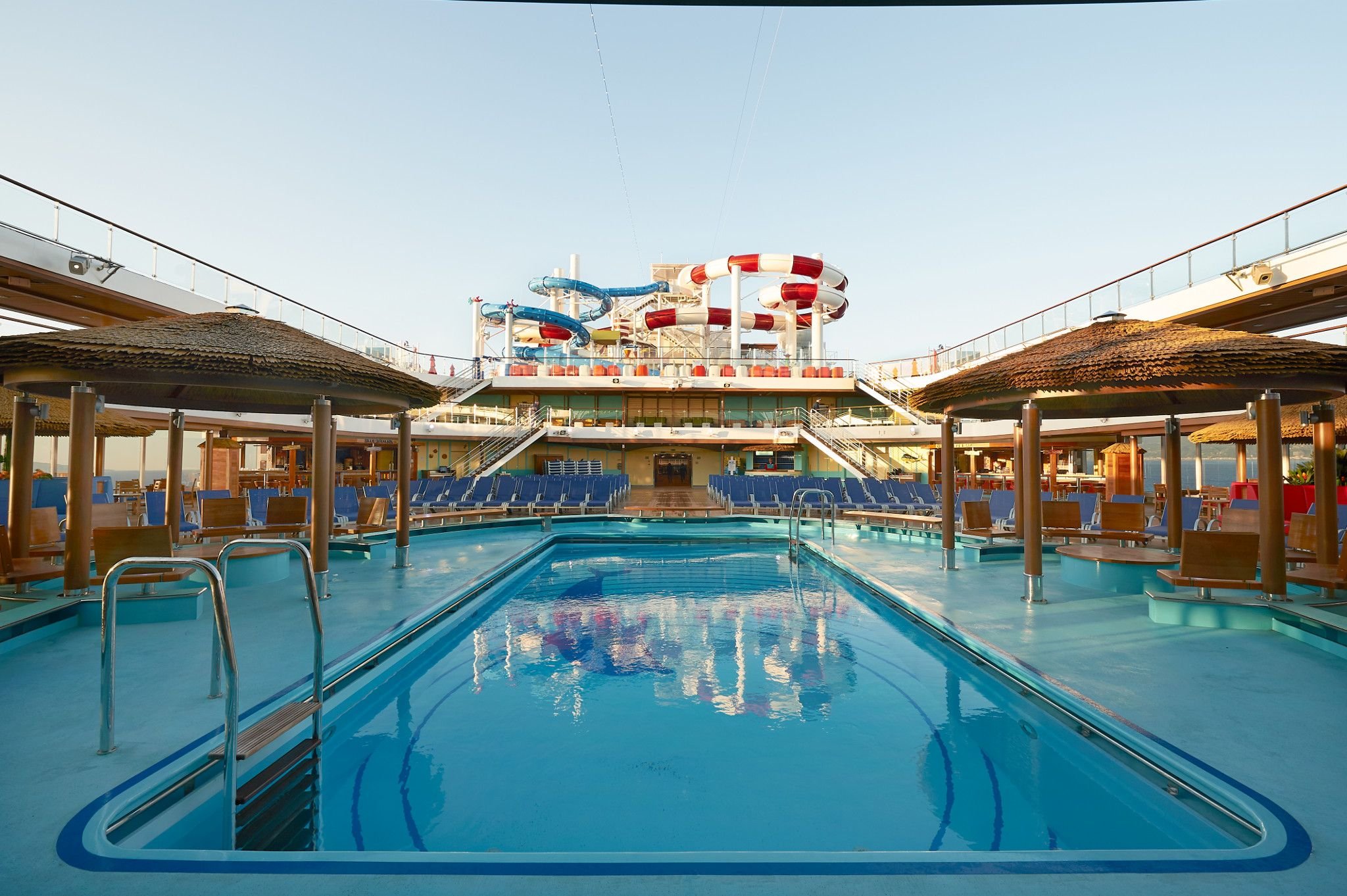 Carnival Horizon aft pool flanked by thatched shade huts, looking toward the WaterWorks slides