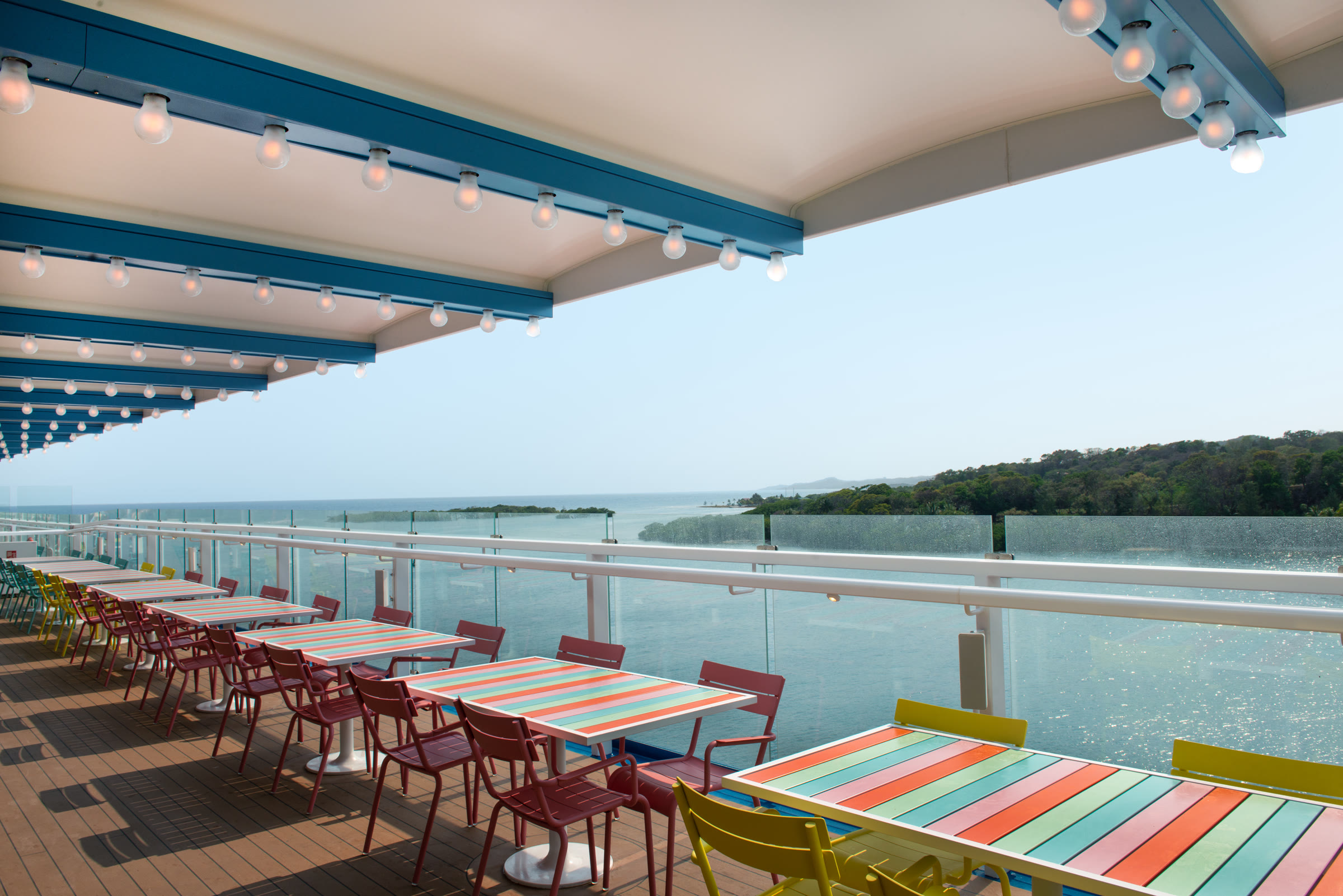 Sunny Shores deck seating with colorful tables and ocean view aboard Carnival Jubilee