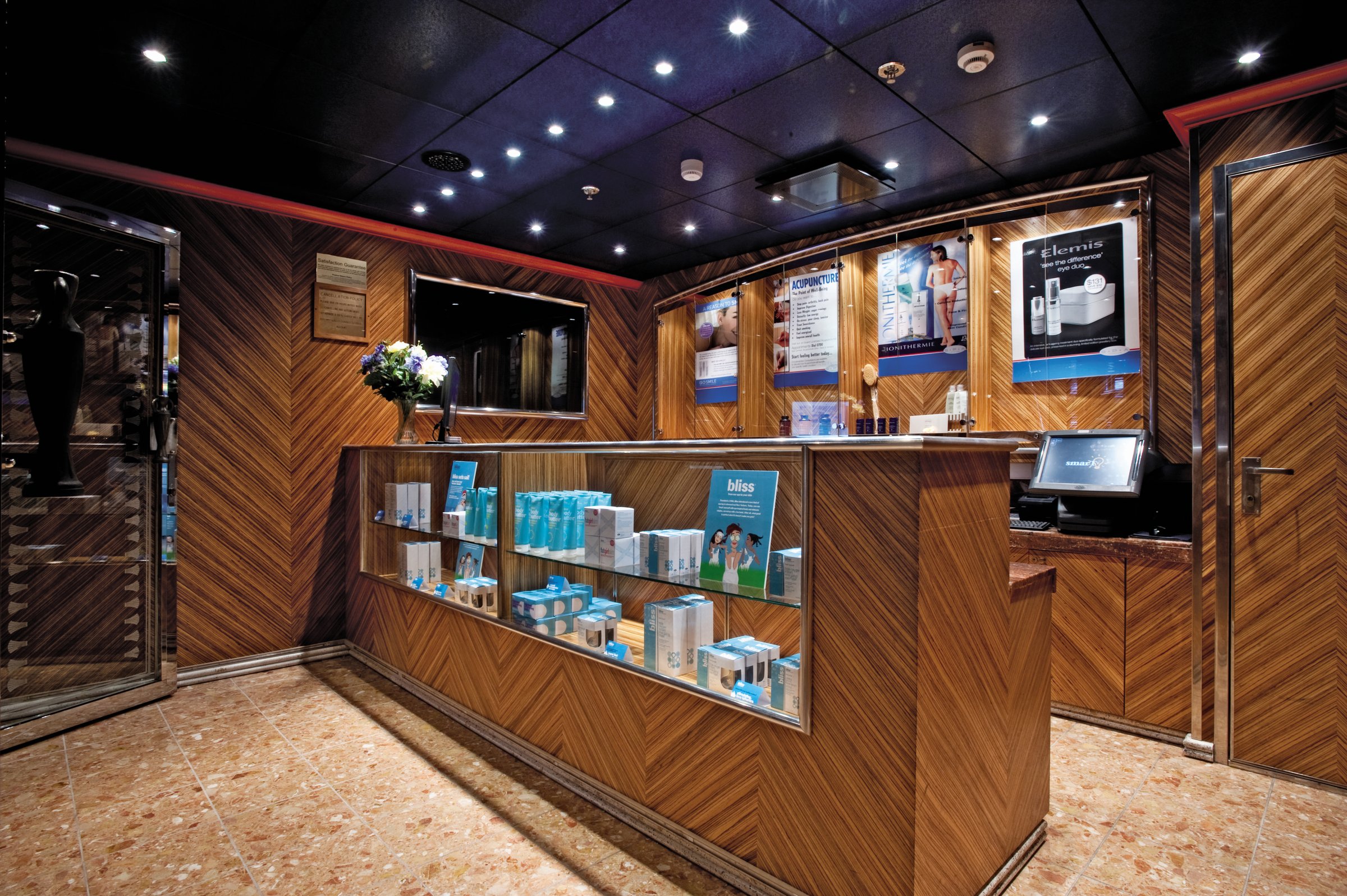Carnival Legend spa reception with wood-panelled retail display and recessed ceiling lights