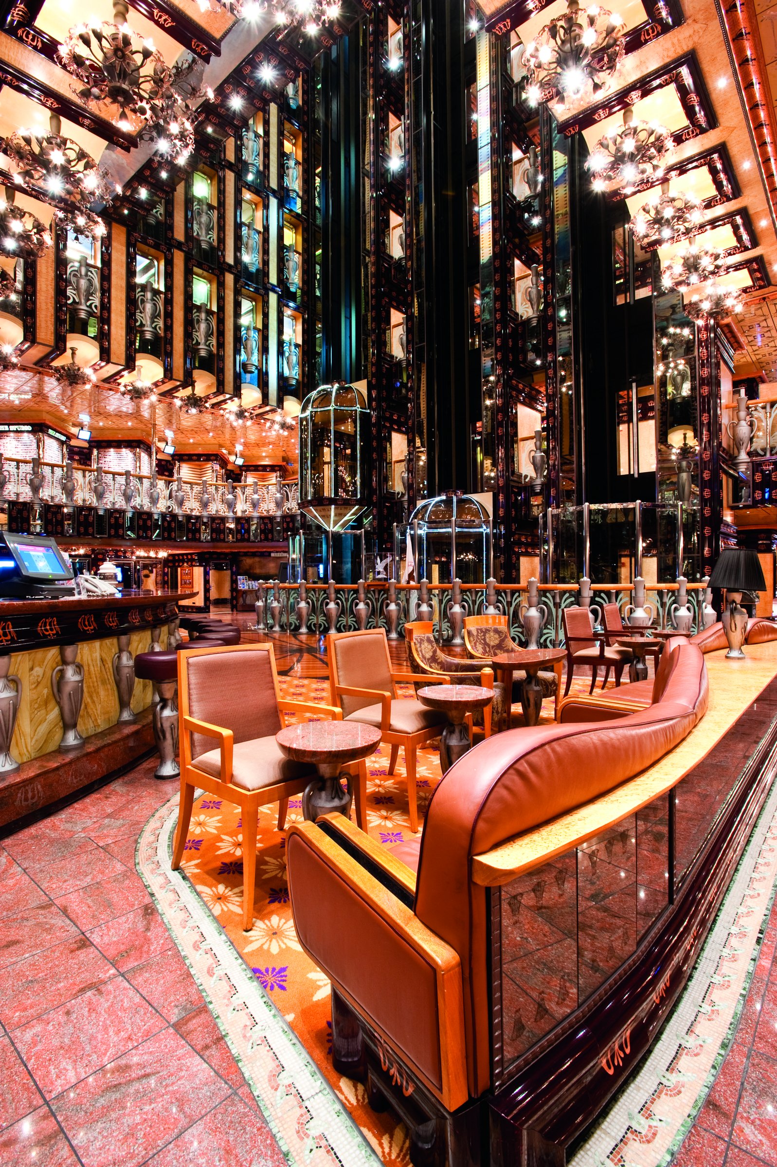 Carnival Legend multi-deck atrium lobby with glass elevators, a bar and orange leather seating