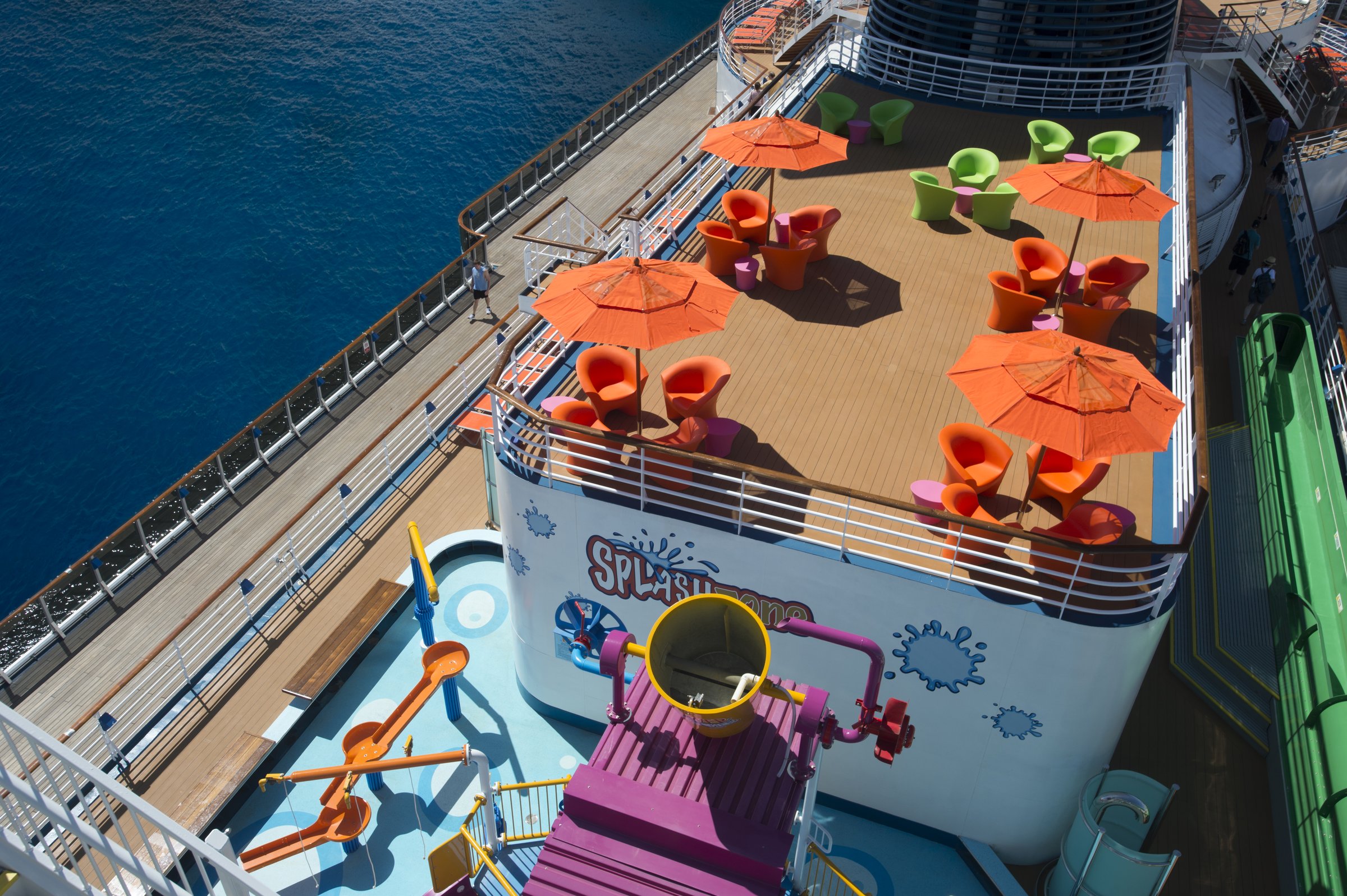 Carnival Legend WaterWorks deck seen from above with orange umbrellas, lounge chairs and a splash feature