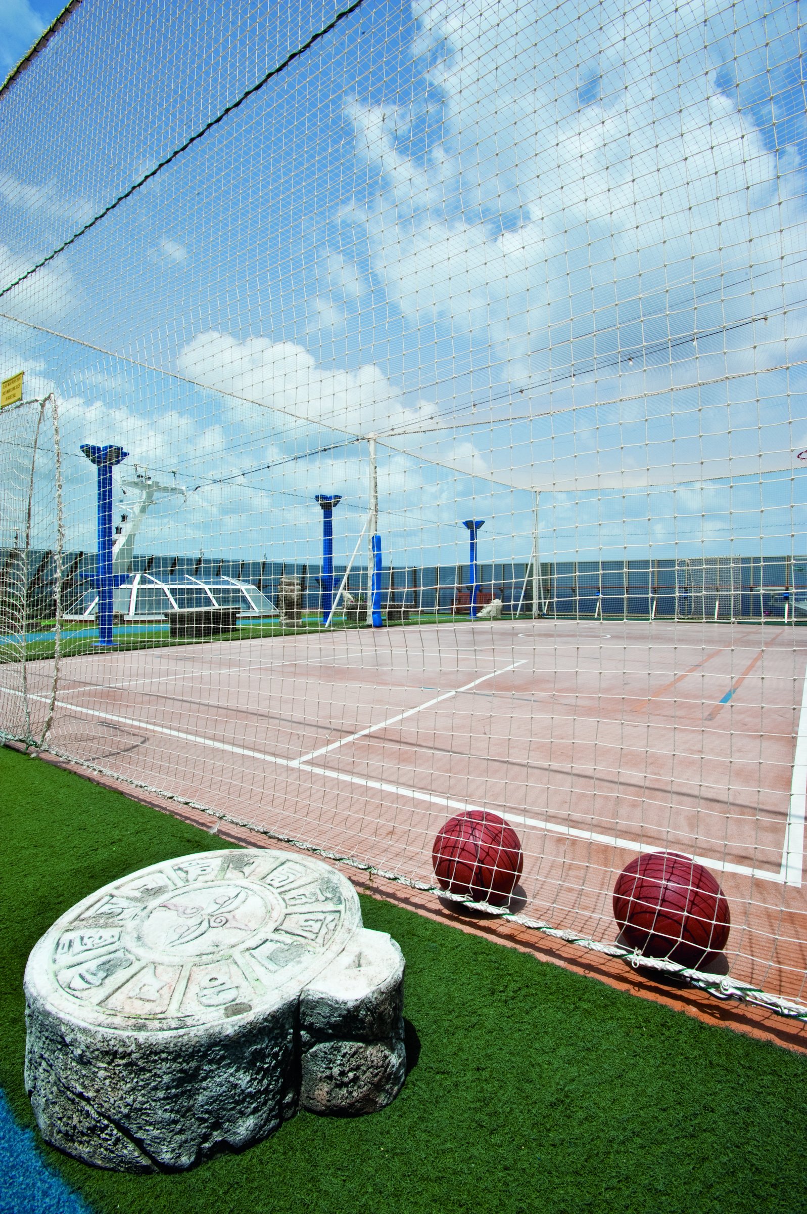 Carnival Legend sport deck with netted court and turf area under blue sky