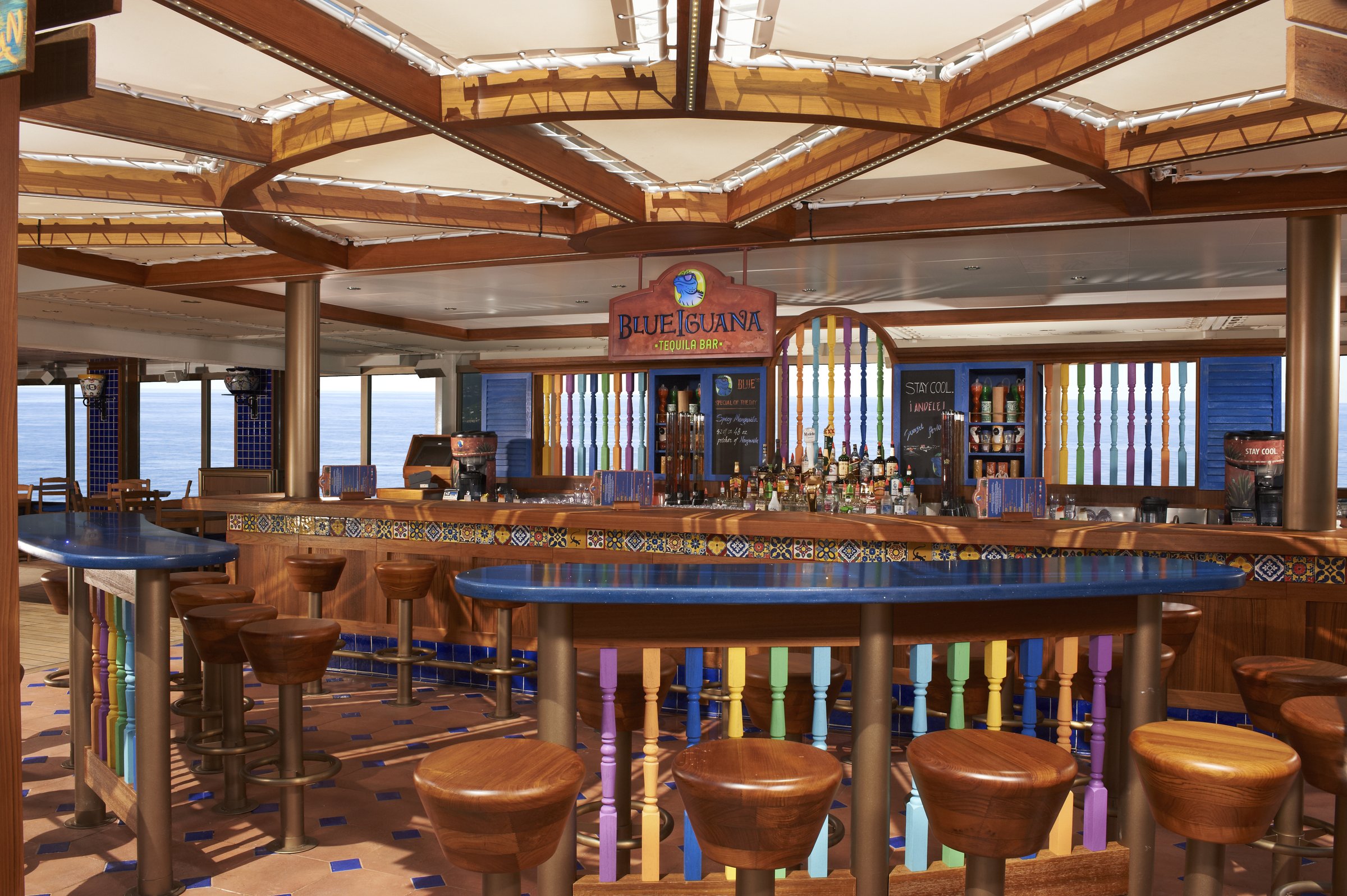 Carnival Liberty Blue Iguana Bar with round wooden stools, a blue-topped counter and coloured balusters