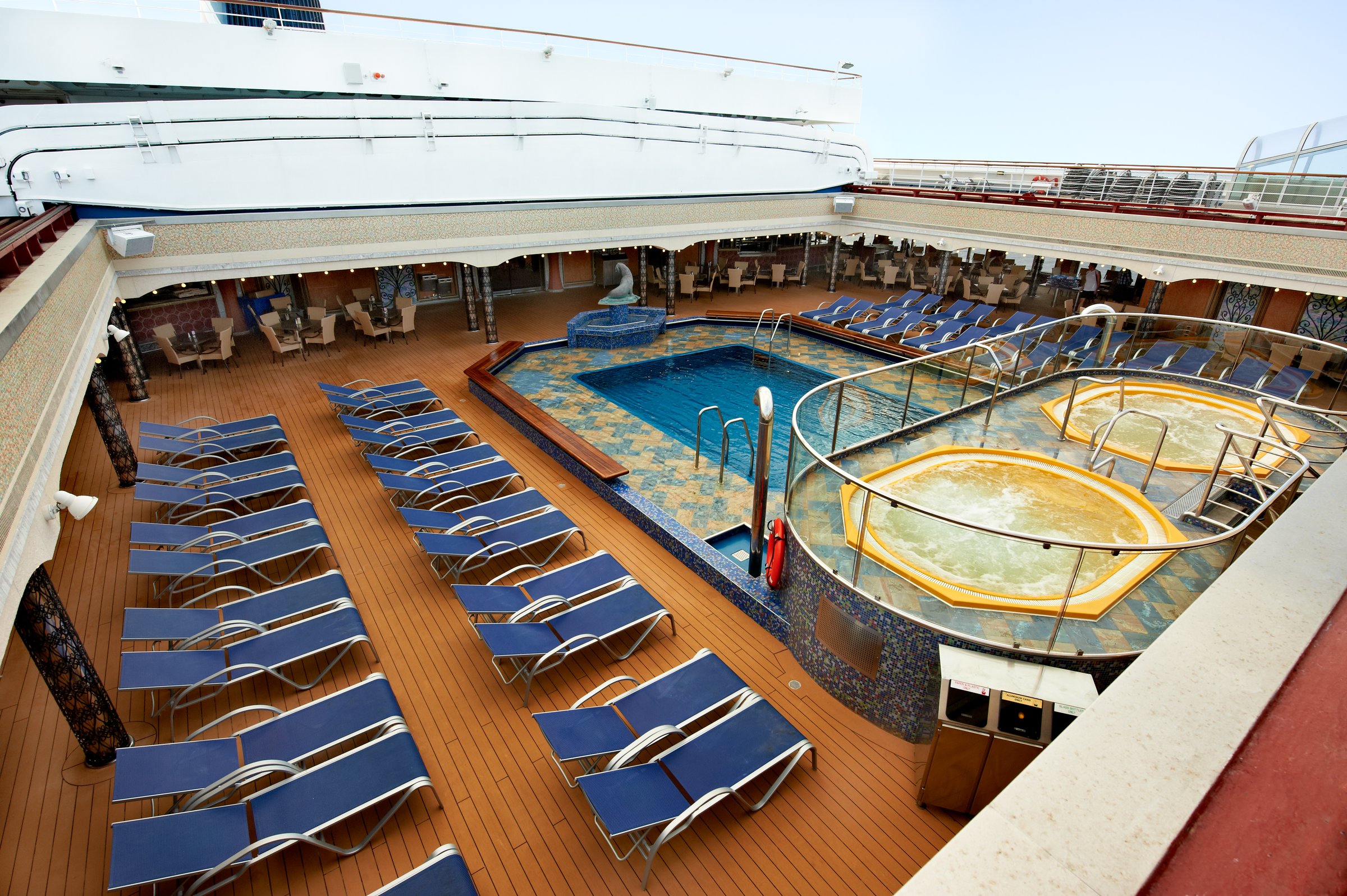 Carnival Liberty Versailles aft pool deck from above, with blue loungers and two hot tubs