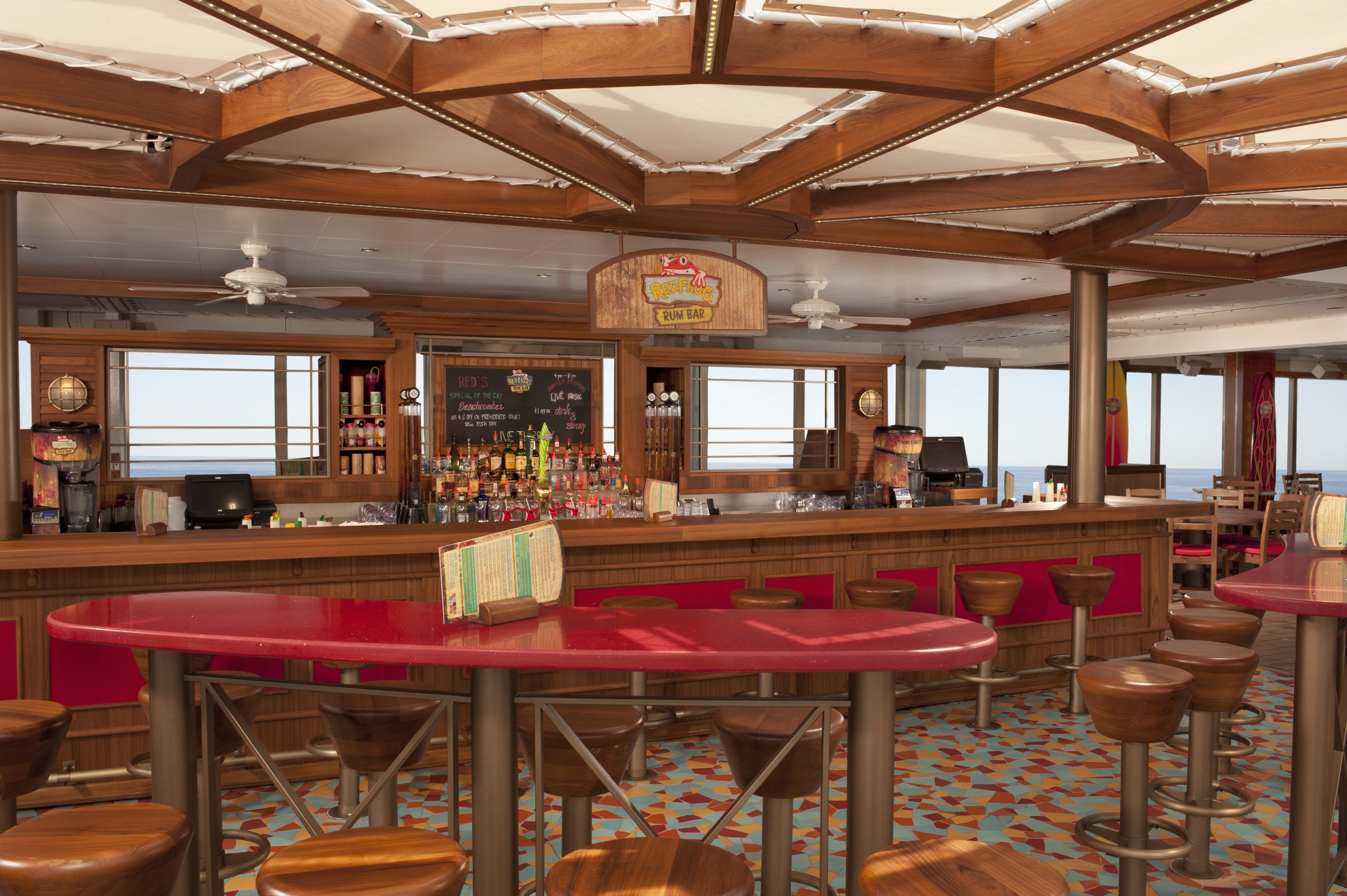 Carnival Liberty Red Frog Pub with a red-topped table, barrel stools and a wooden-beamed ceiling