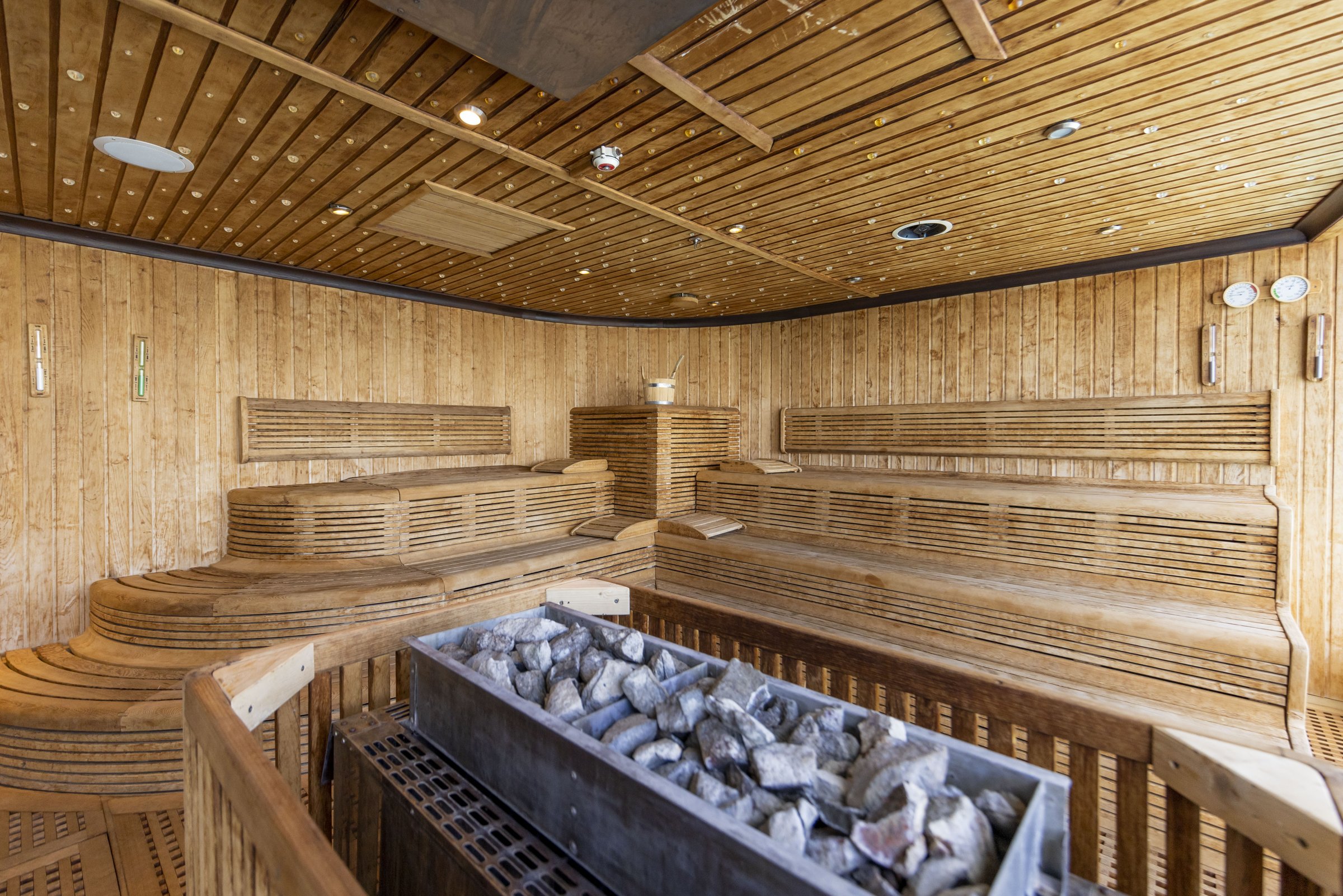 Carnival Luminosa Cloud 9 Spa sauna with tiered wooden benches and a stone-filled heater