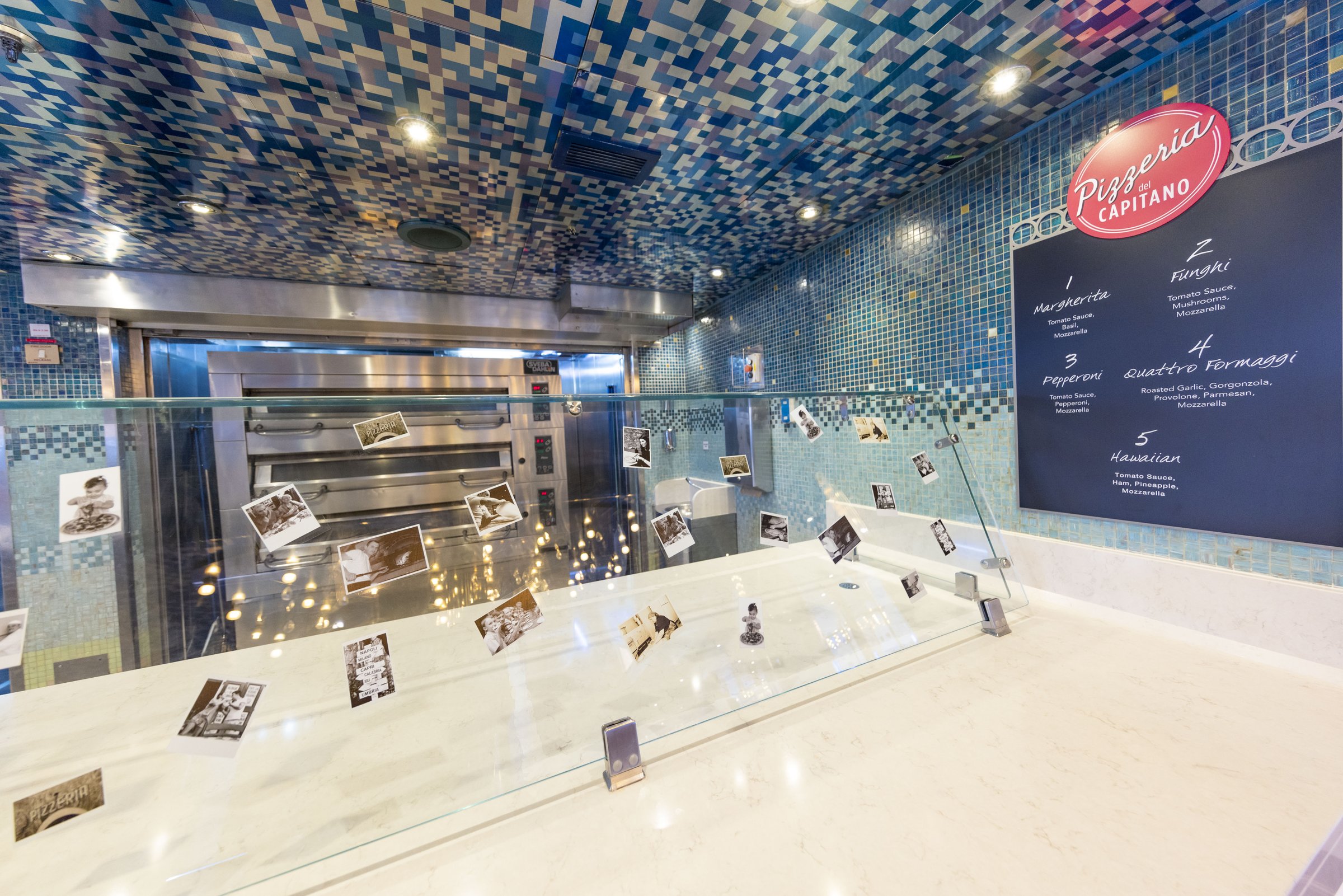 Carnival Luminosa pizzeria counter with a blue mosaic ceiling, glass-fronted oven and menu board