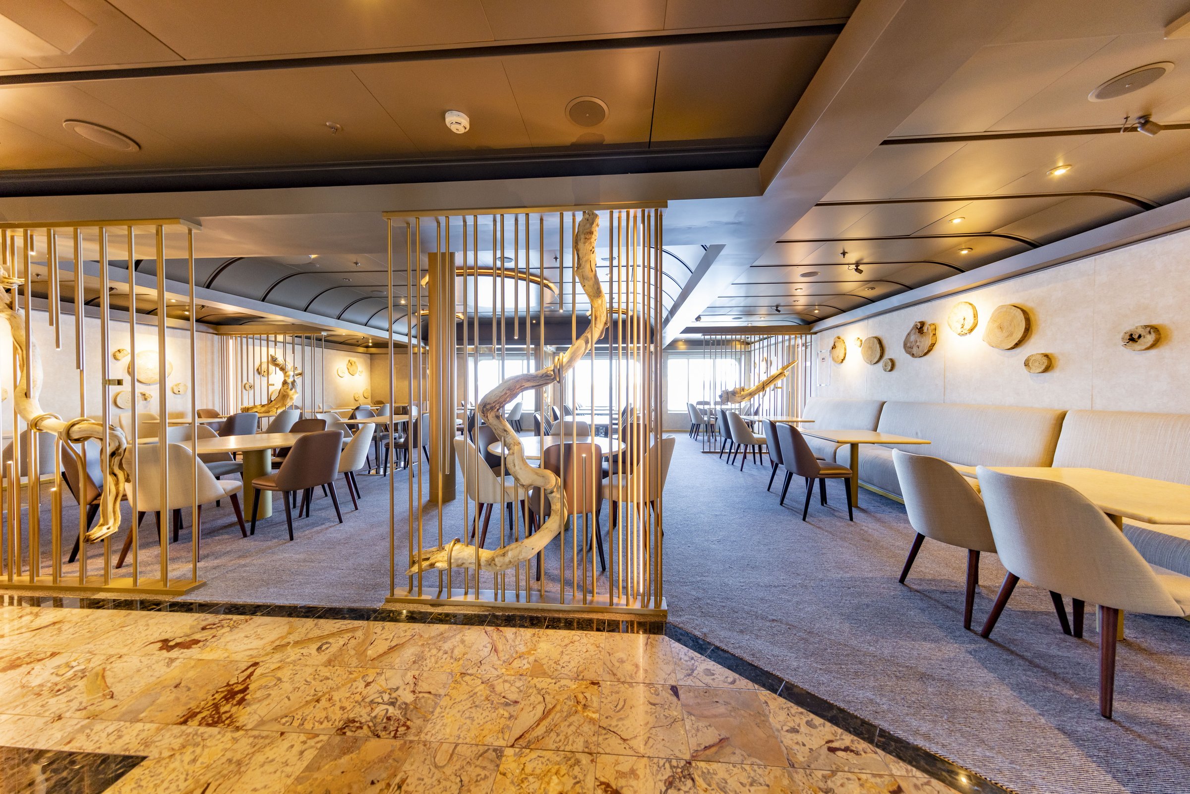 Carnival Luminosa Archipelago Restaurant with driftwood-style gold screens and light cream seating