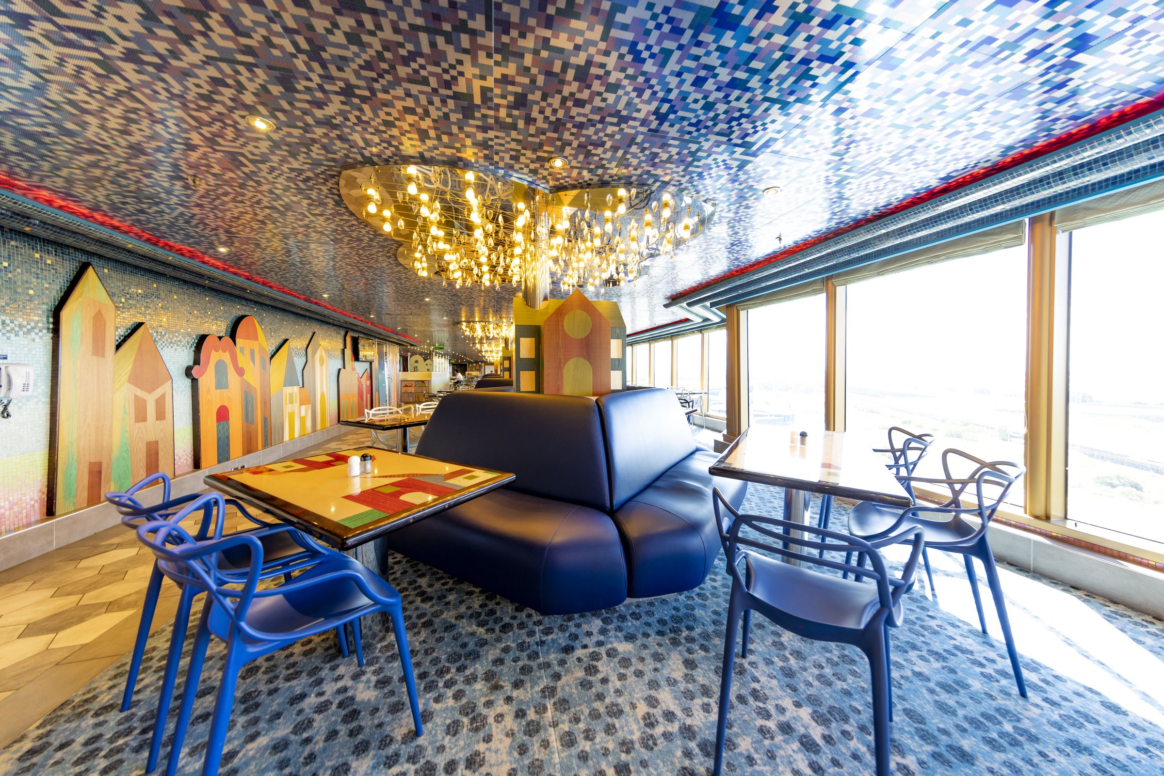 Carnival Luminosa Lido dining area with mosaic ceiling, blue chairs and panoramic windows