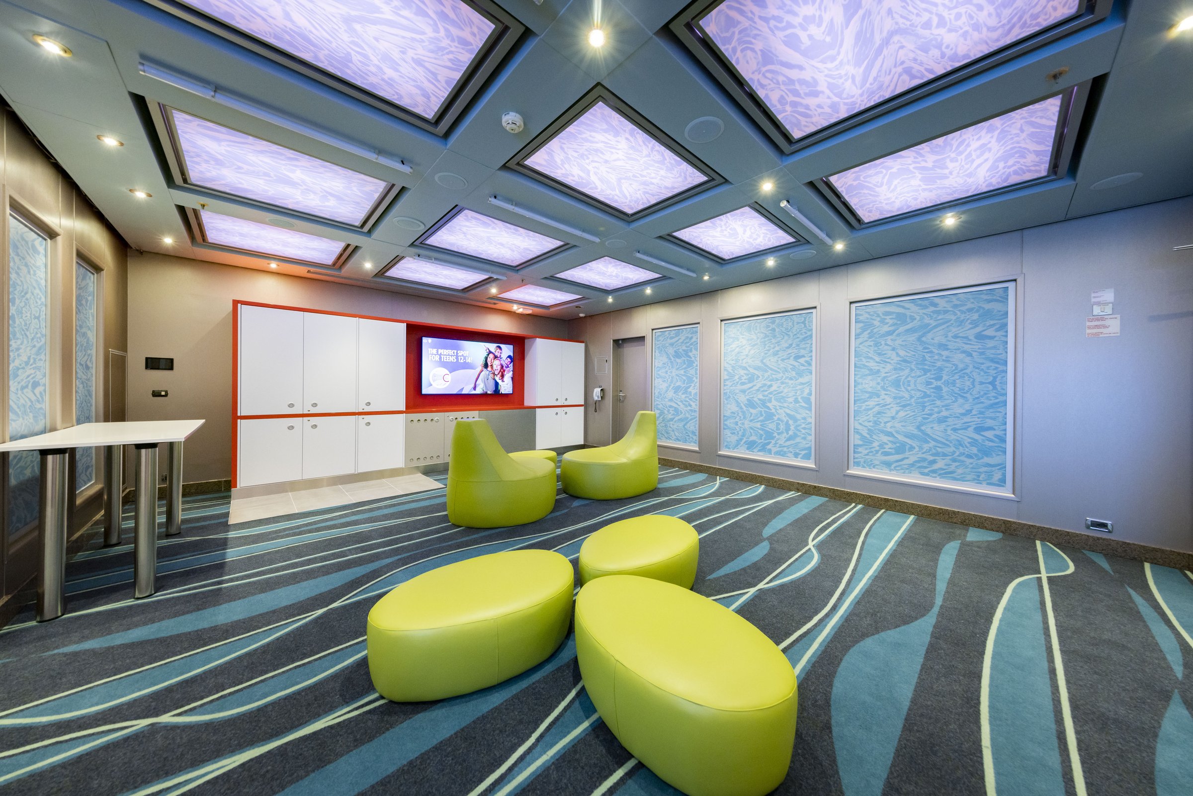 Carnival Luminosa Circle C youth lounge with lime-green poufs, wave-pattern carpet and a TV