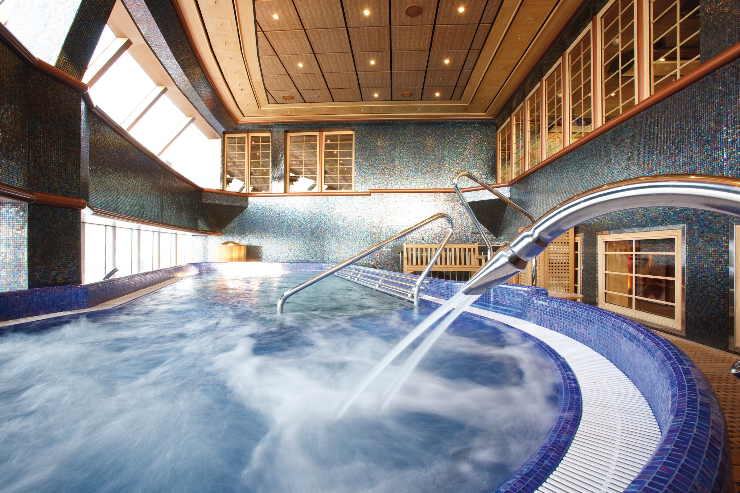 Carnival Luminosa Cloud 9 Spa thalassotherapy pool with a water jet and blue mosaic tiling