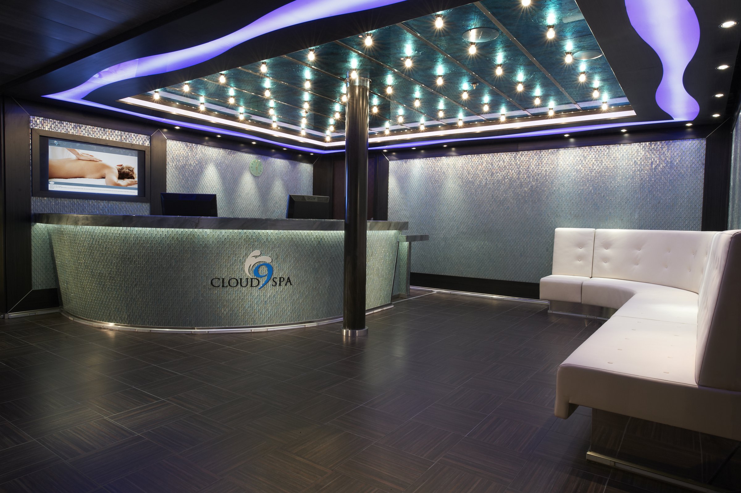 Carnival Magic Cloud 9 Spa reception with a mosaic-fronted desk, white sofa and LED-lit ceiling